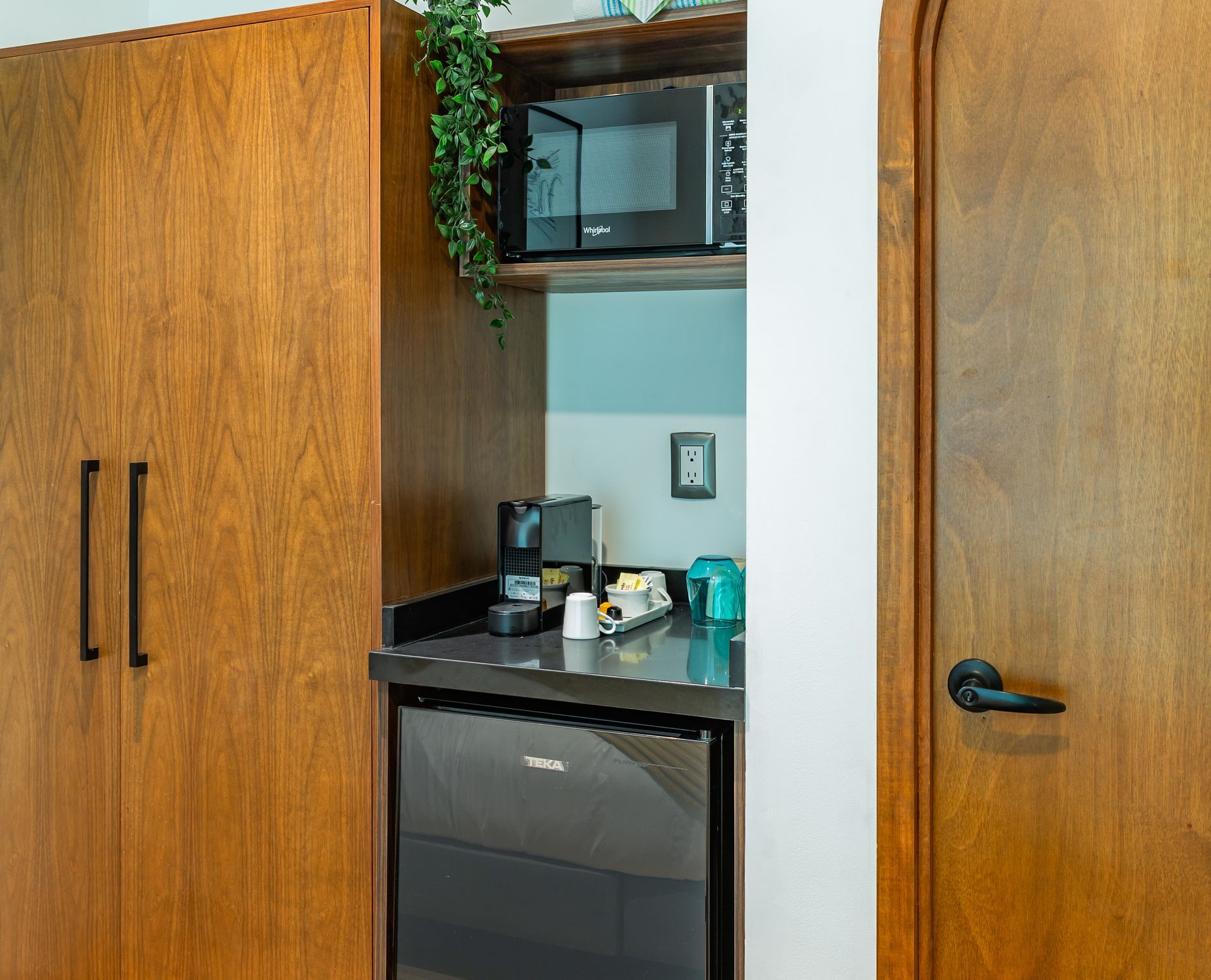 Una cocina con microondas, refrigerador y cafetera.
