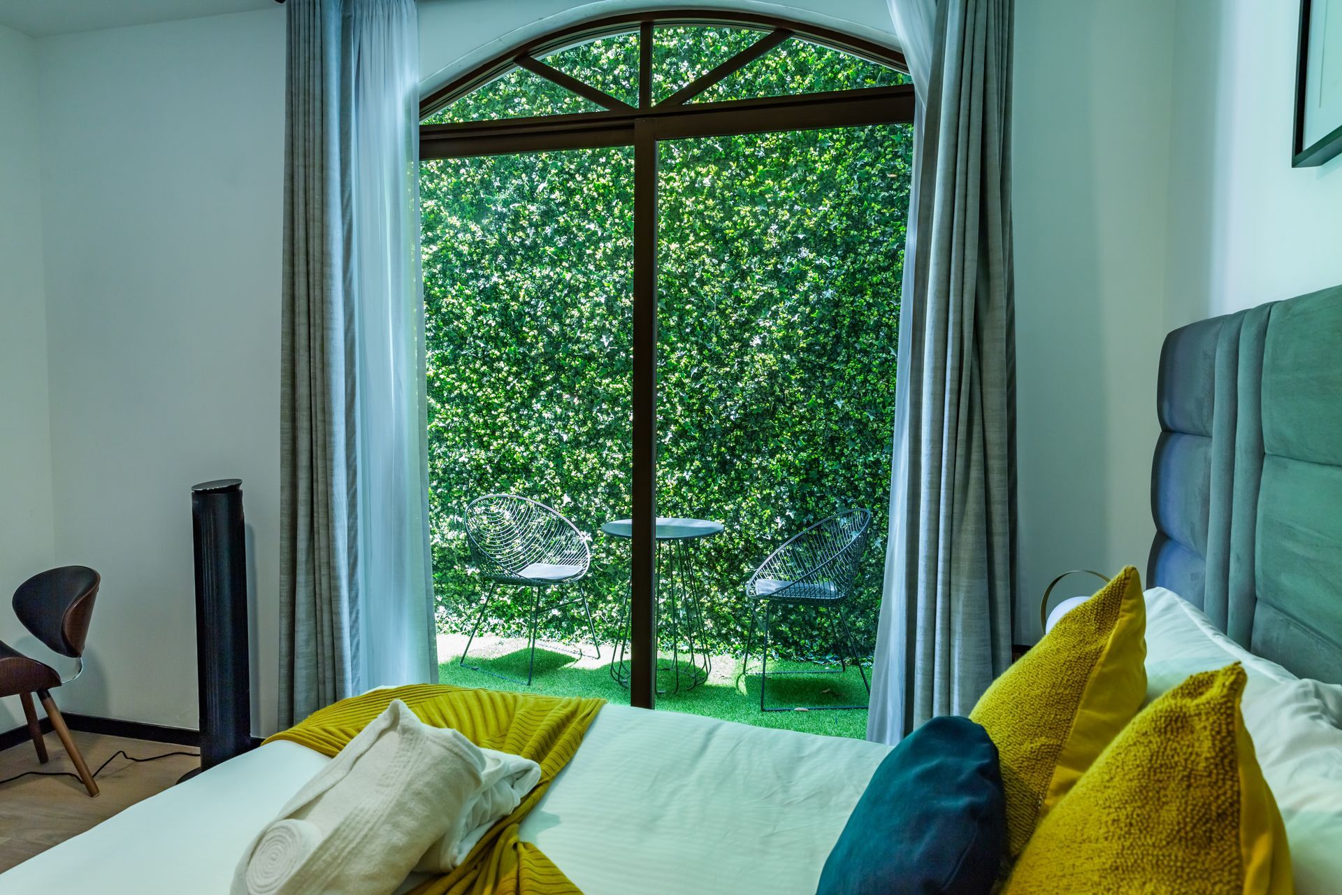 Un dormitorio con una gran ventana y una cama con almohadas amarillas.