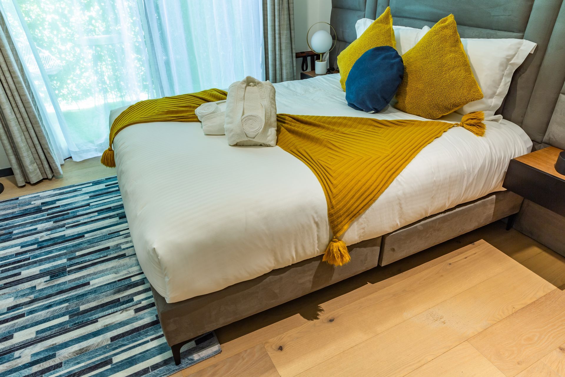 Una cama con sábanas blancas y almohadas amarillas en una habitación de hotel.