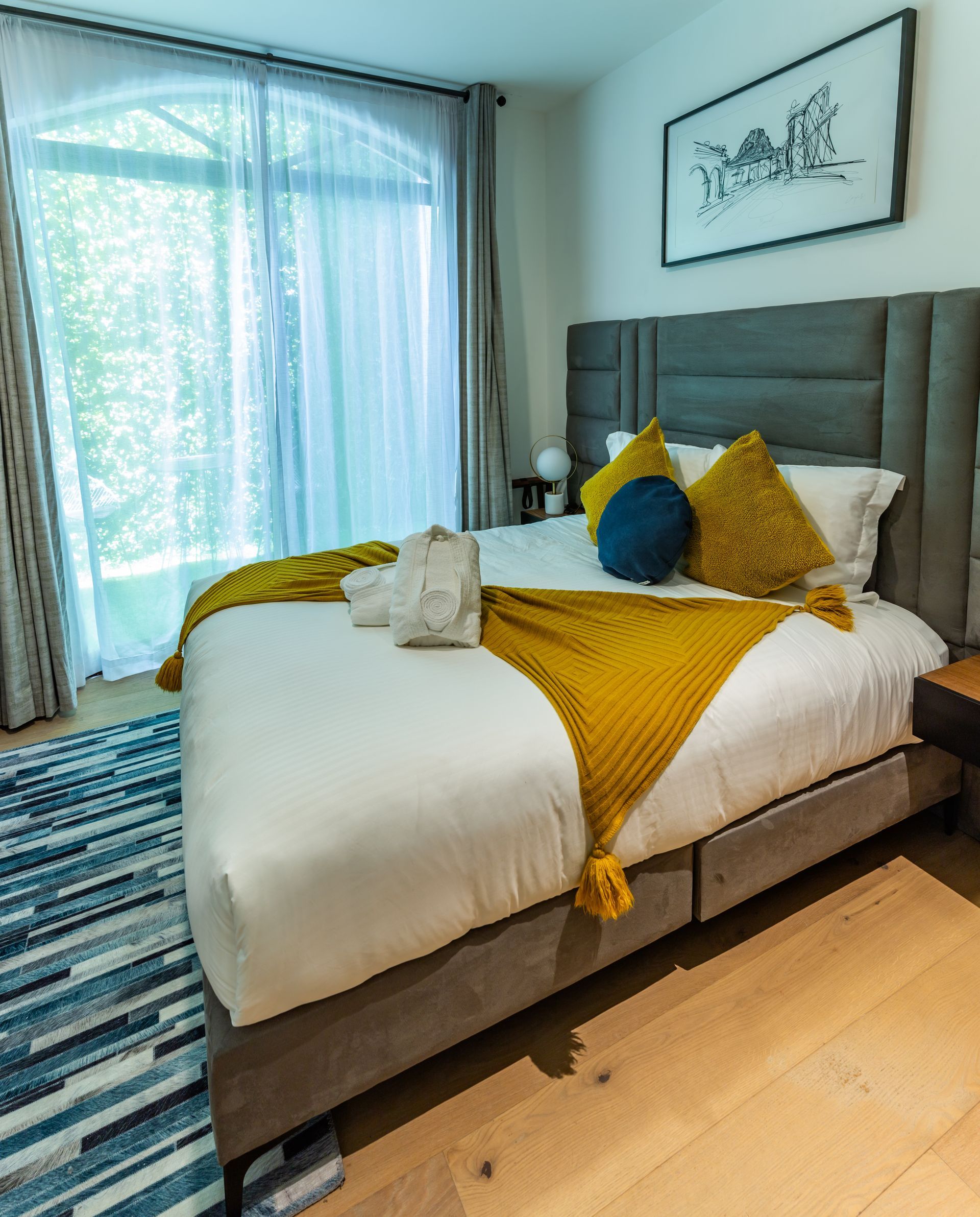 Un dormitorio con una cama grande, una alfombra y una ventana.