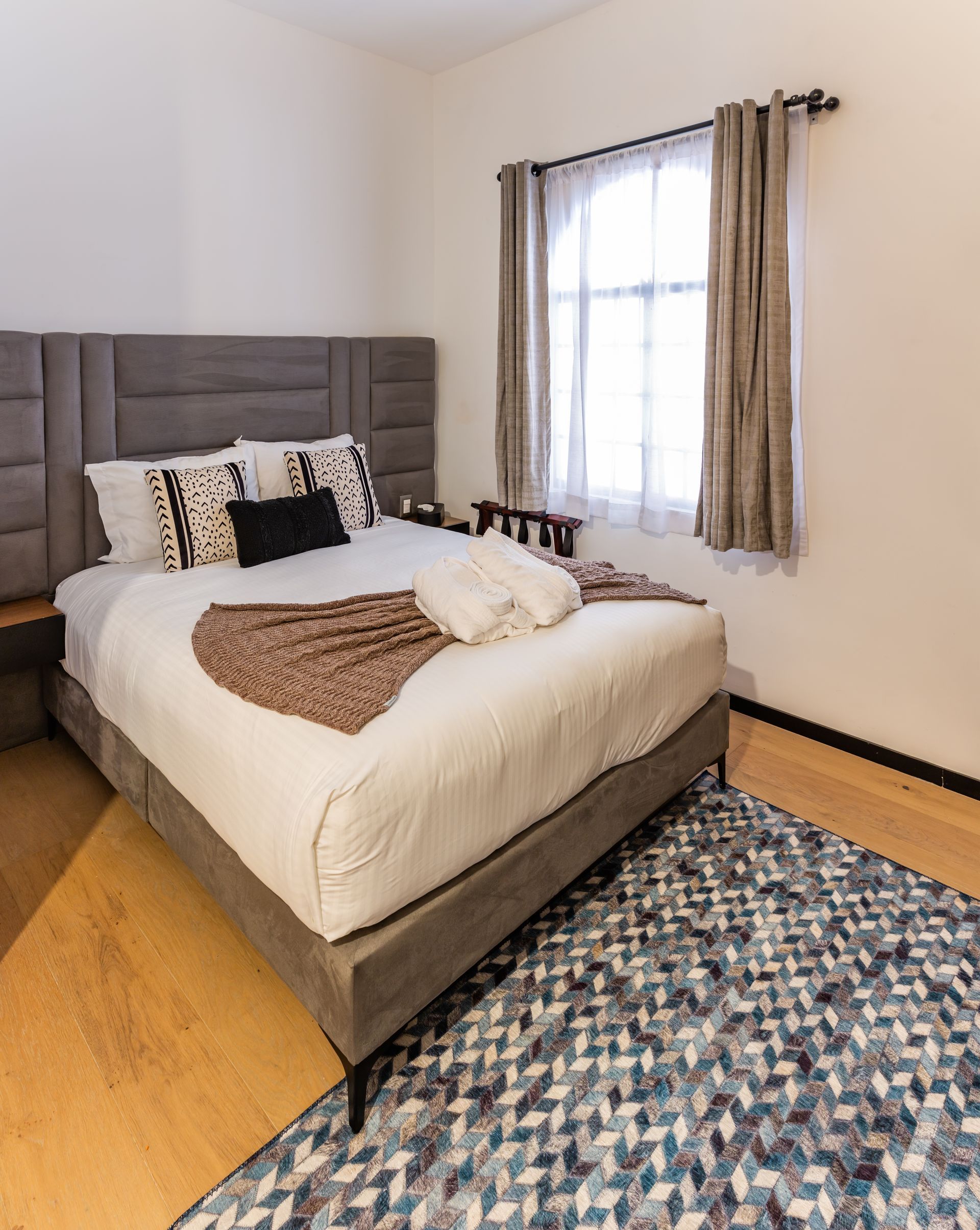 Un dormitorio con cama, alfombra y ventana.