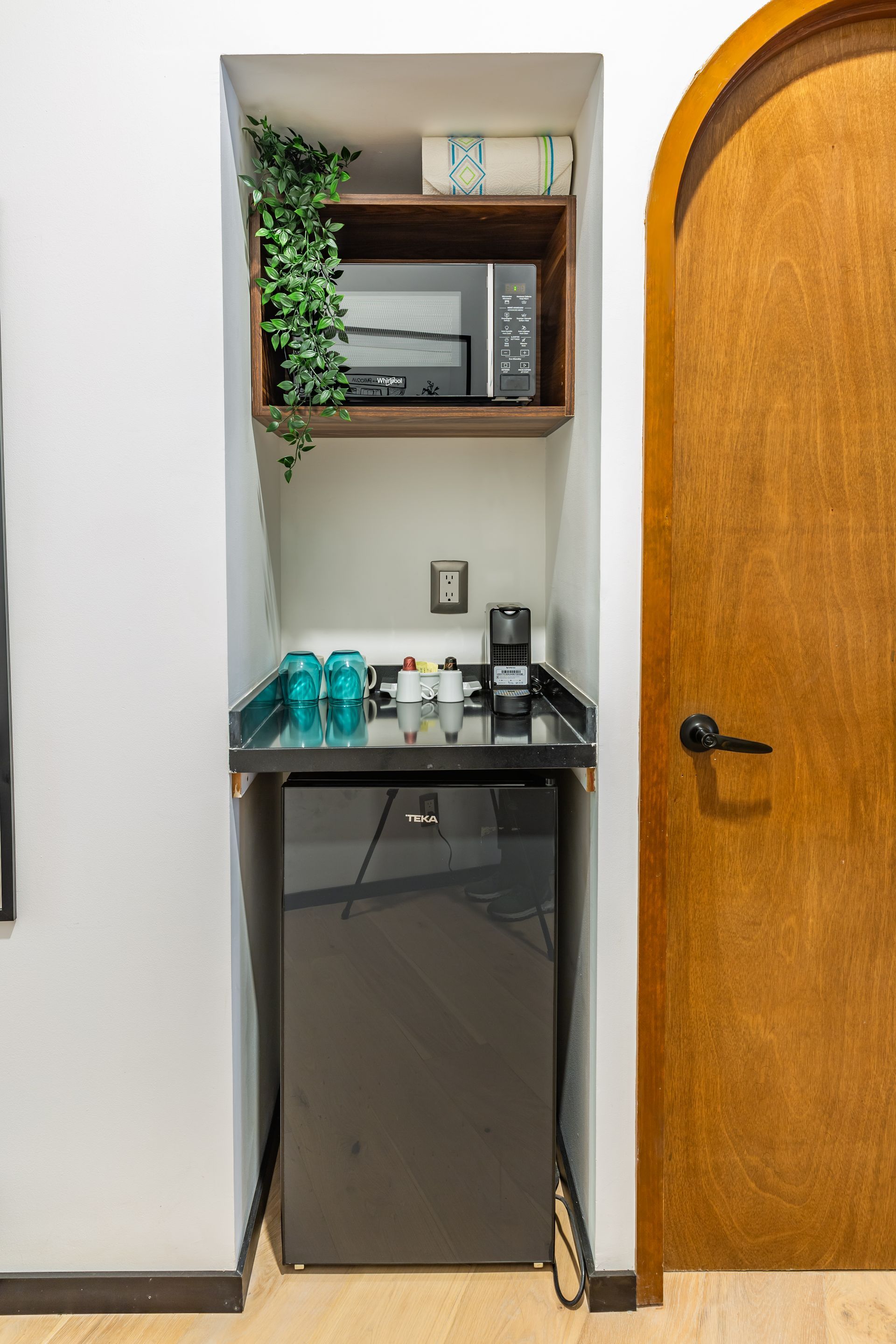 Un pequeño refrigerador está en un rincón de una habitación, al lado de una puerta.