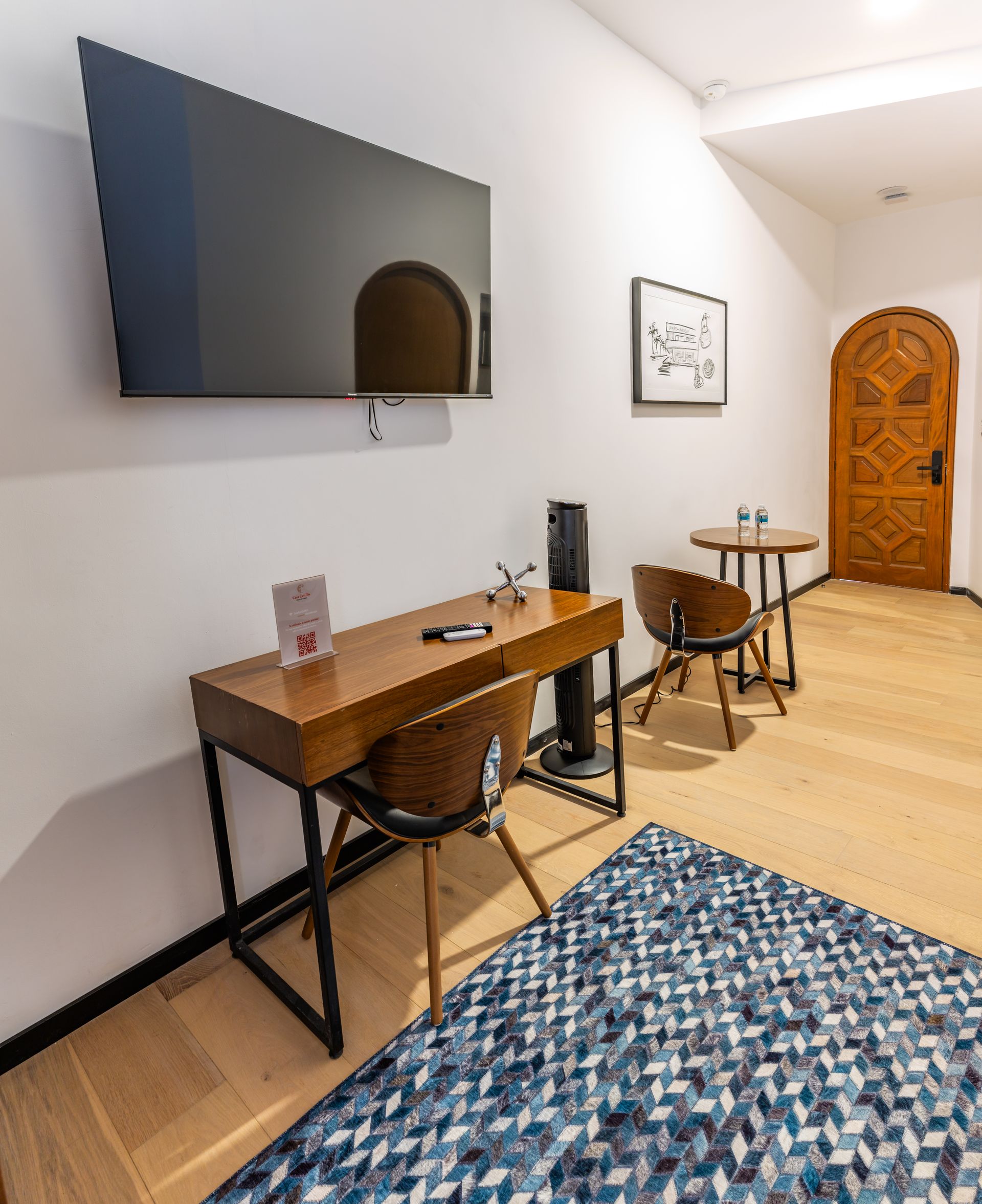 Una sala de estar con escritorio, sillas, mesas y un televisor de pantalla plana.