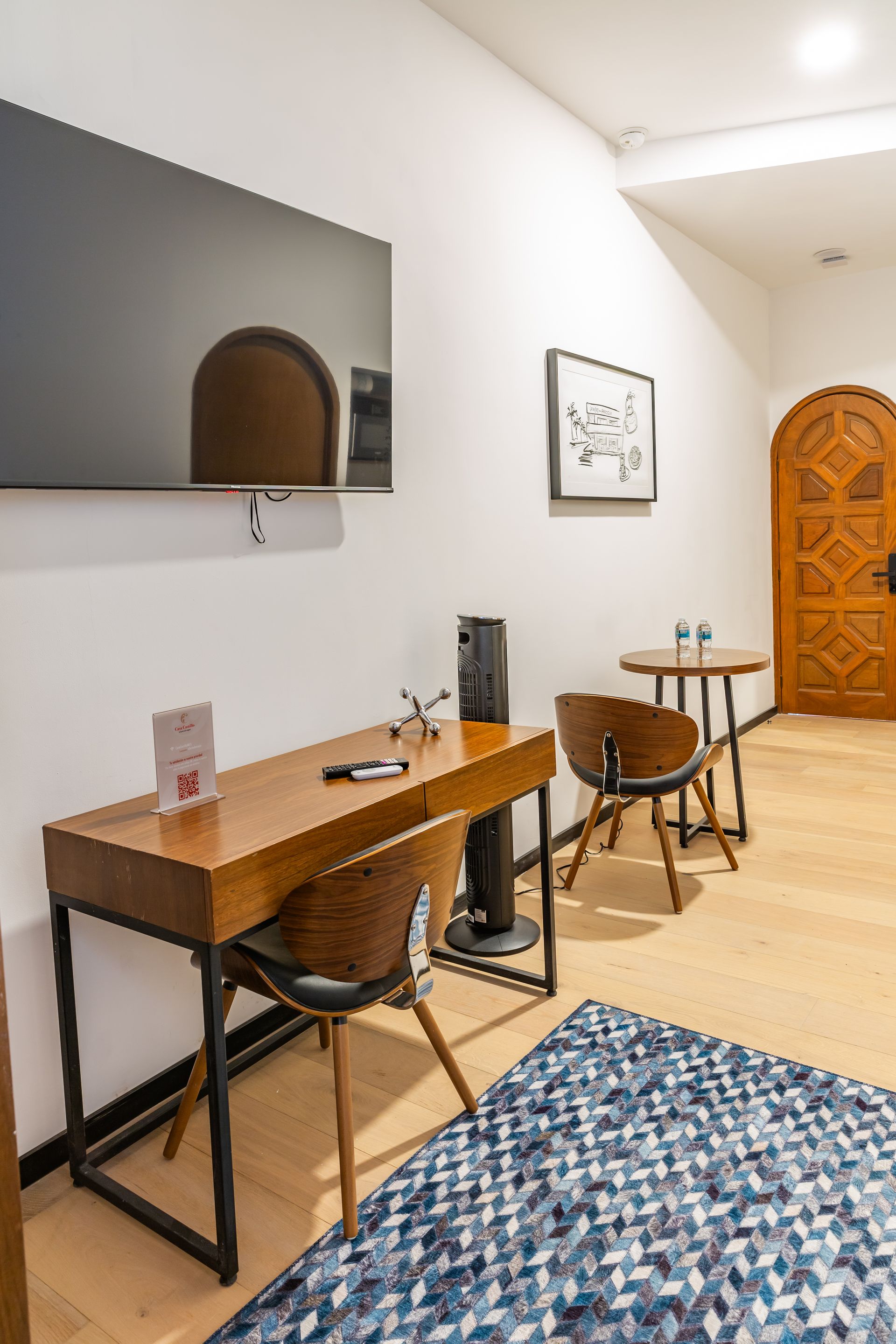 Una habitación con escritorio, sillas, mesas y un televisor de pantalla plana.