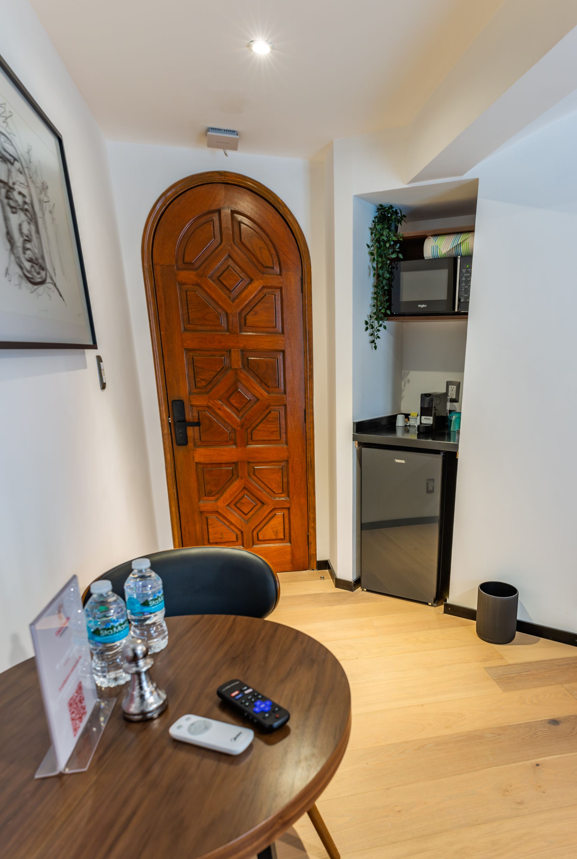Una habitación con una mesa, sillas, un refrigerador y una puerta.