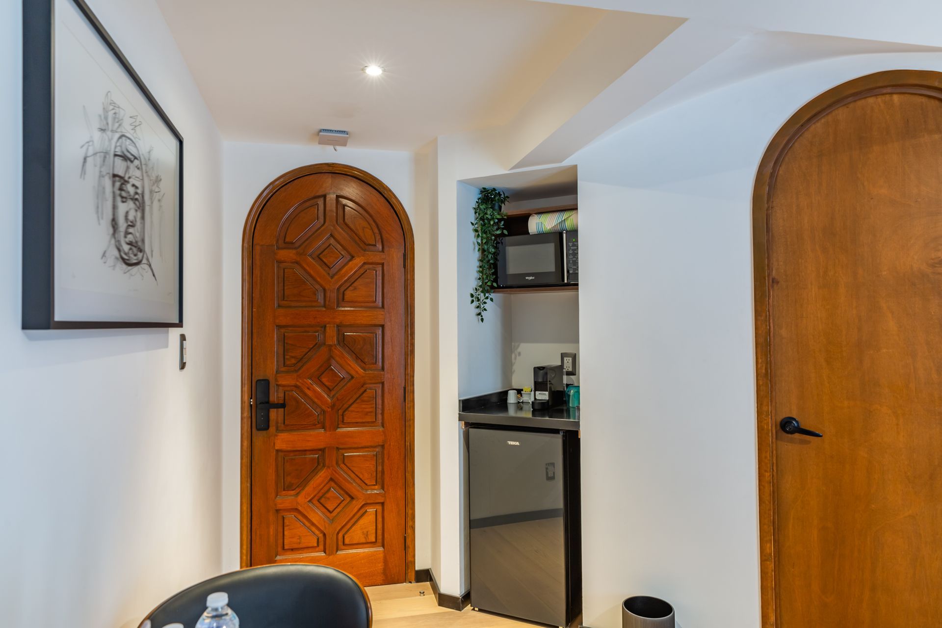 Un pasillo con una puerta de madera y un cuadro en la pared.