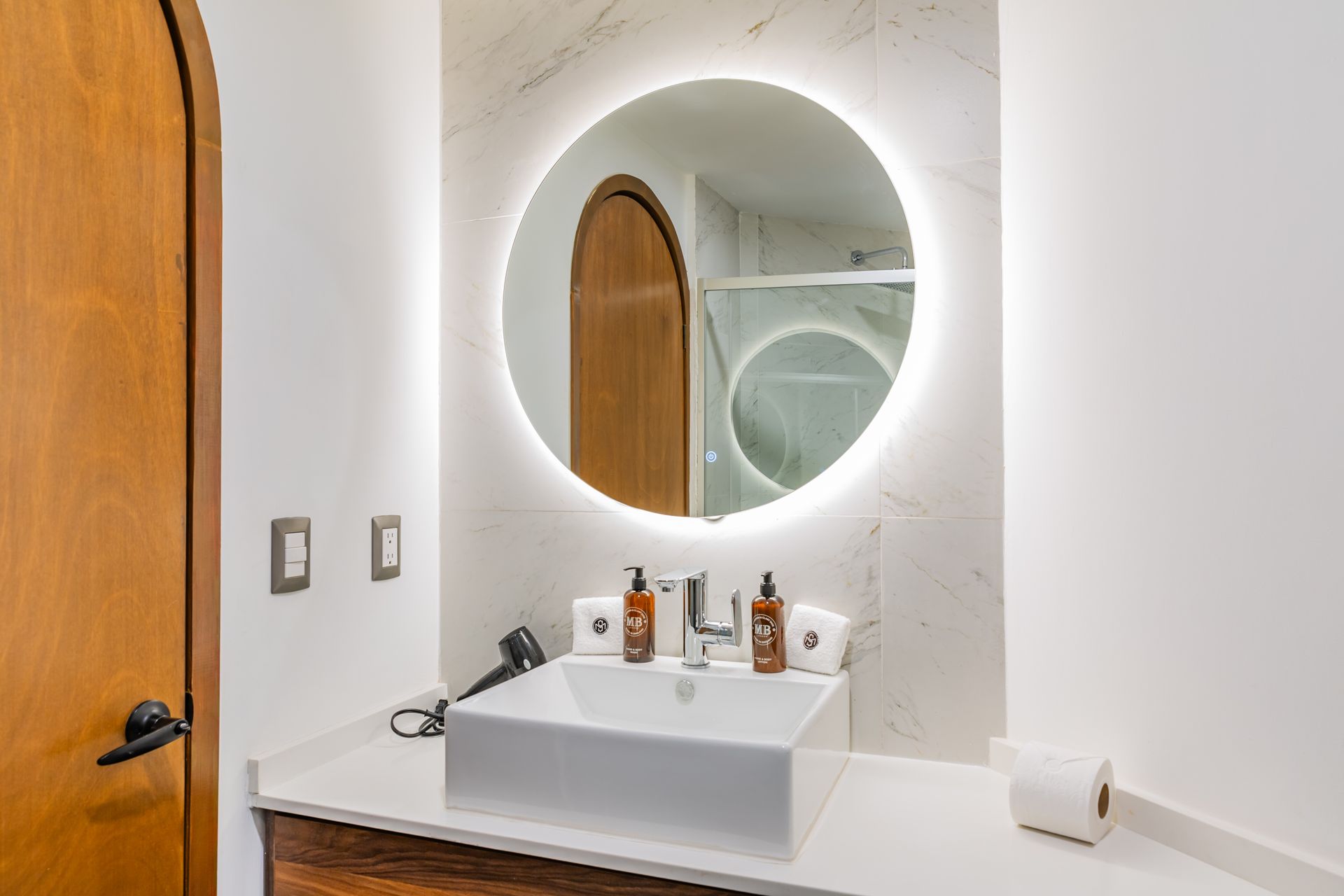 Un baño con lavabo y espejo redondo.