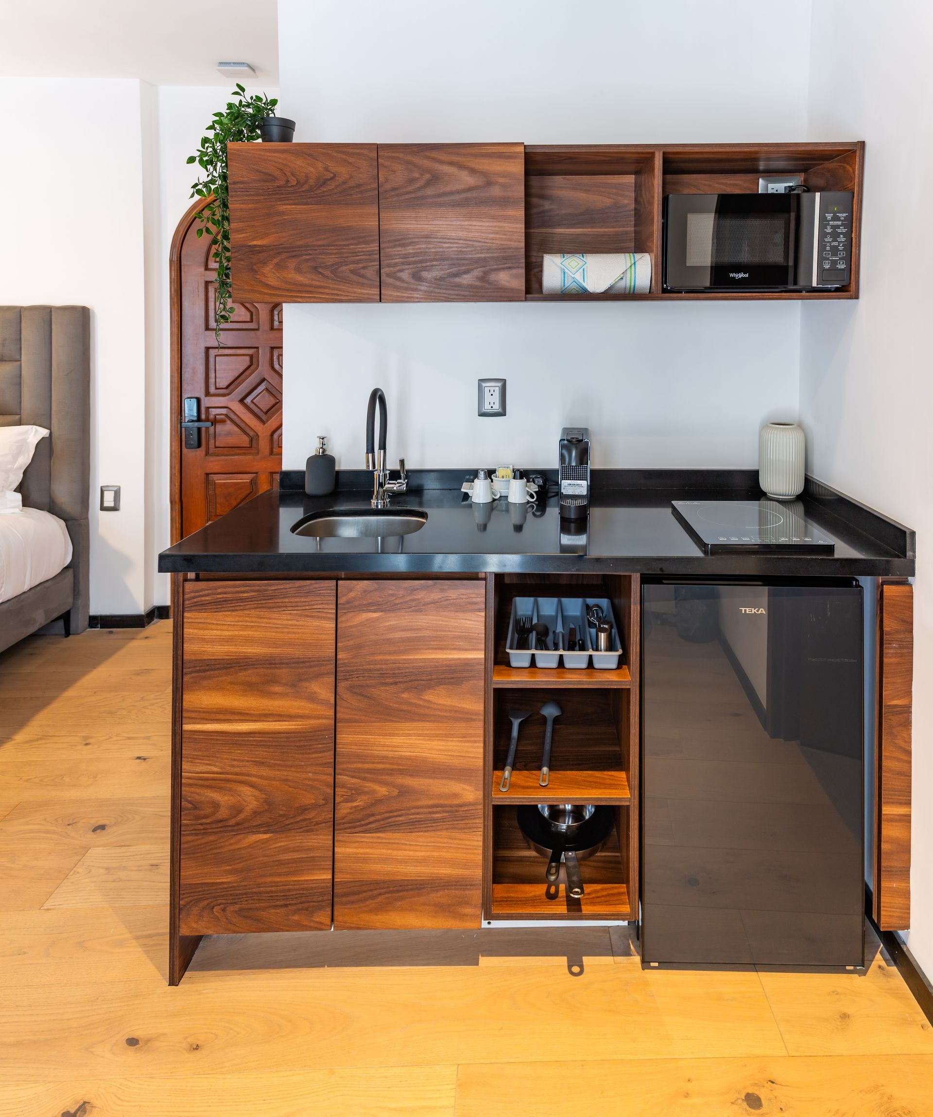 Una pequeña cocina con gabinetes de madera y un refrigerador negro.
