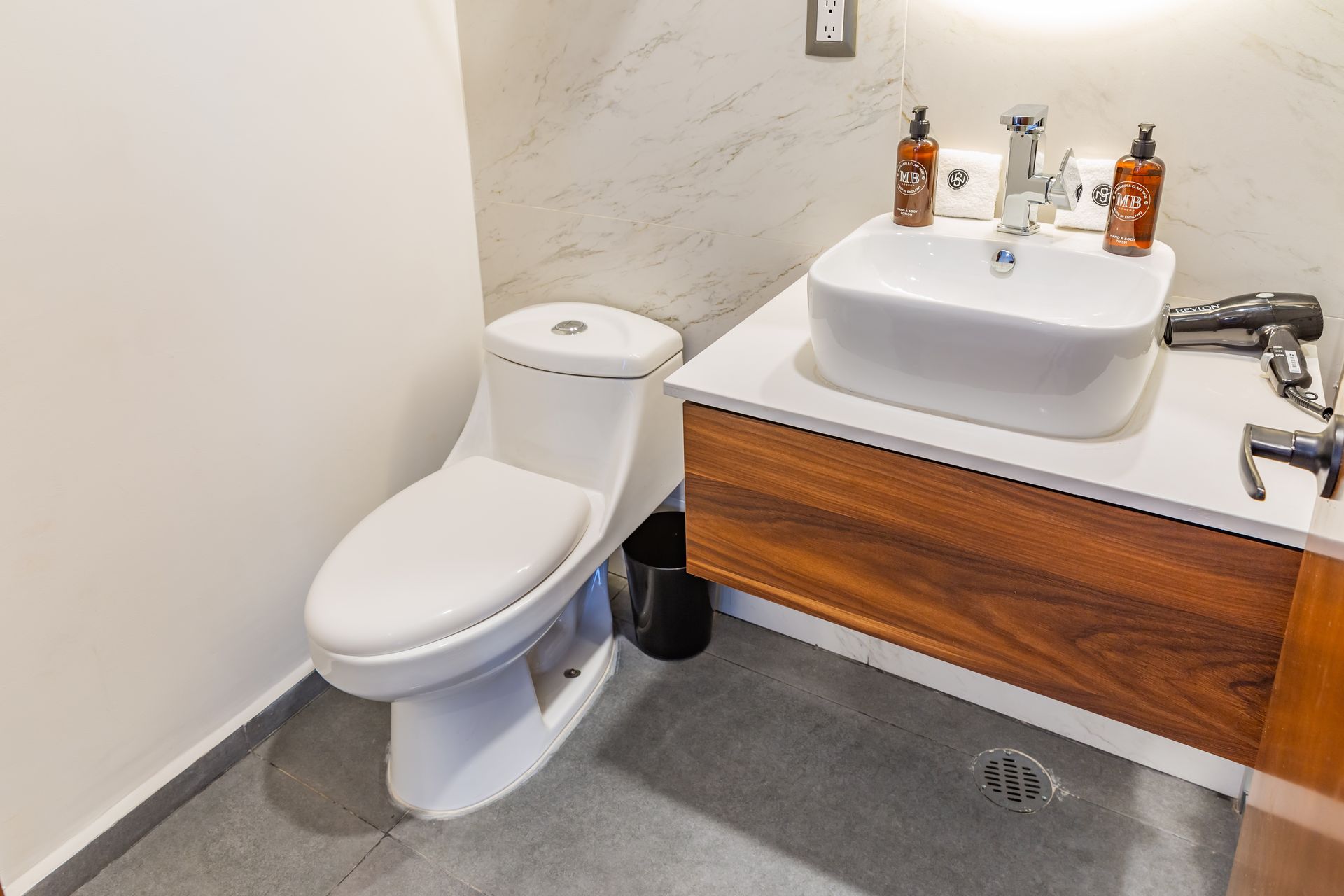 Un baño con inodoro, lavabo y secador de pelo.