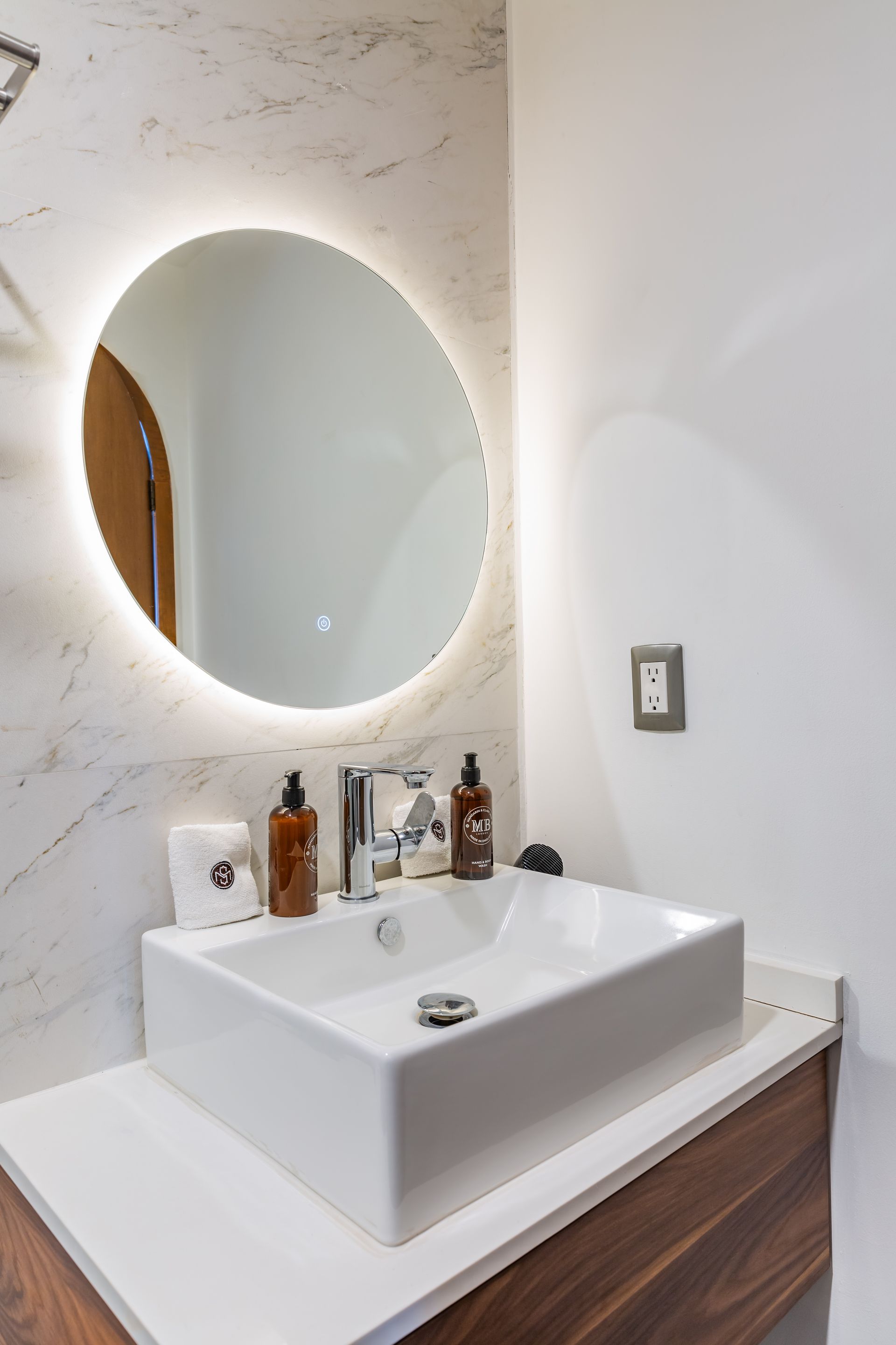 Un baño con lavabo y espejo redondo.