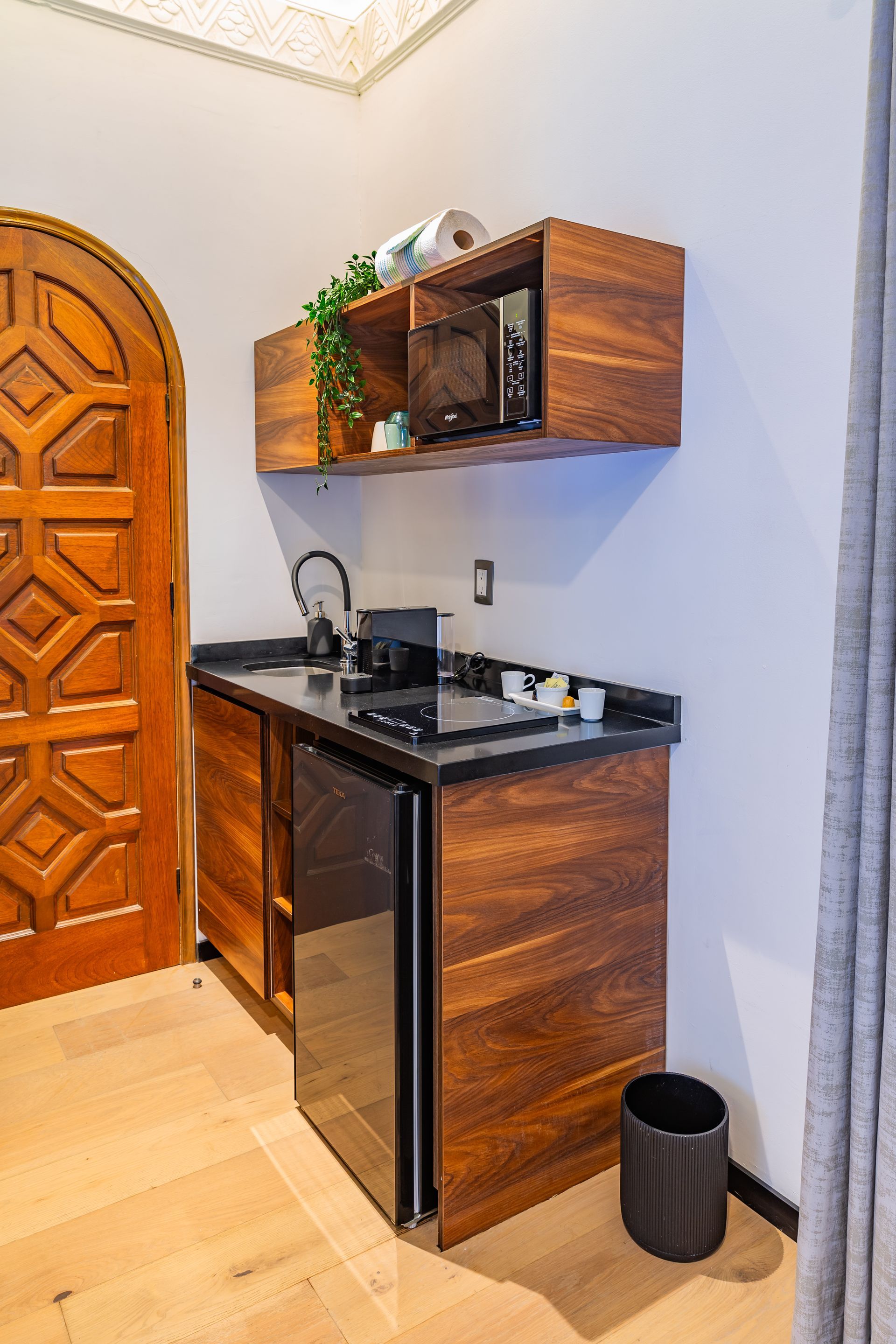 Una pequeña cocina con gabinetes de madera y un refrigerador de acero inoxidable.