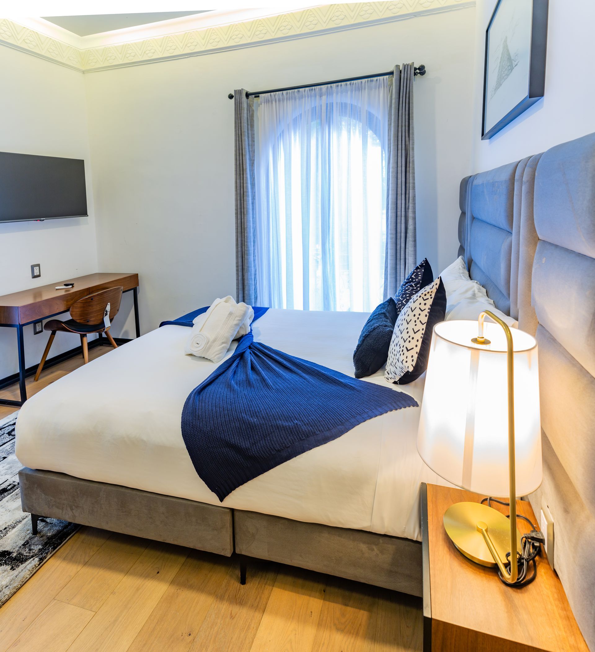 Un dormitorio con dos camas, un escritorio, una lámpara y un televisor.