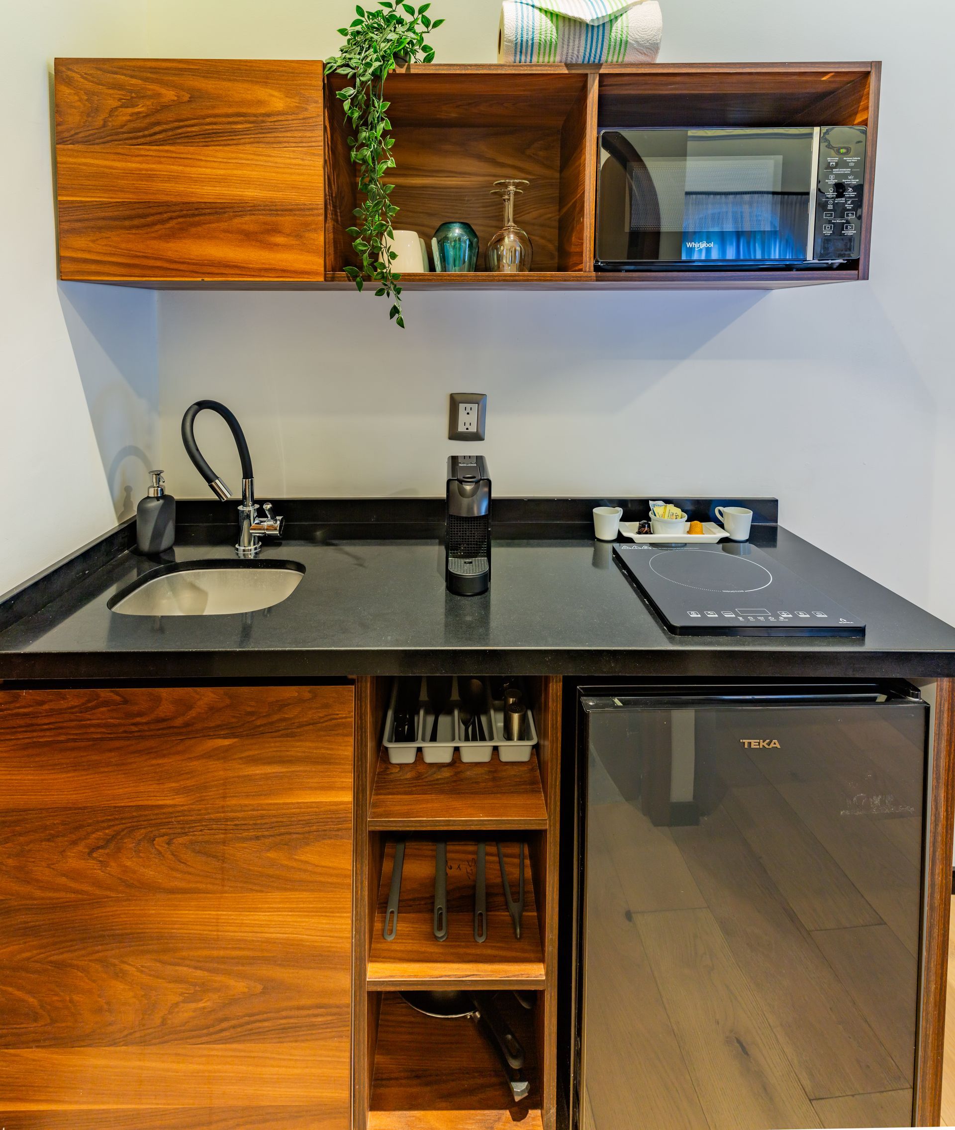 Una pequeña cocina con fregadero, frigorífico y microondas.