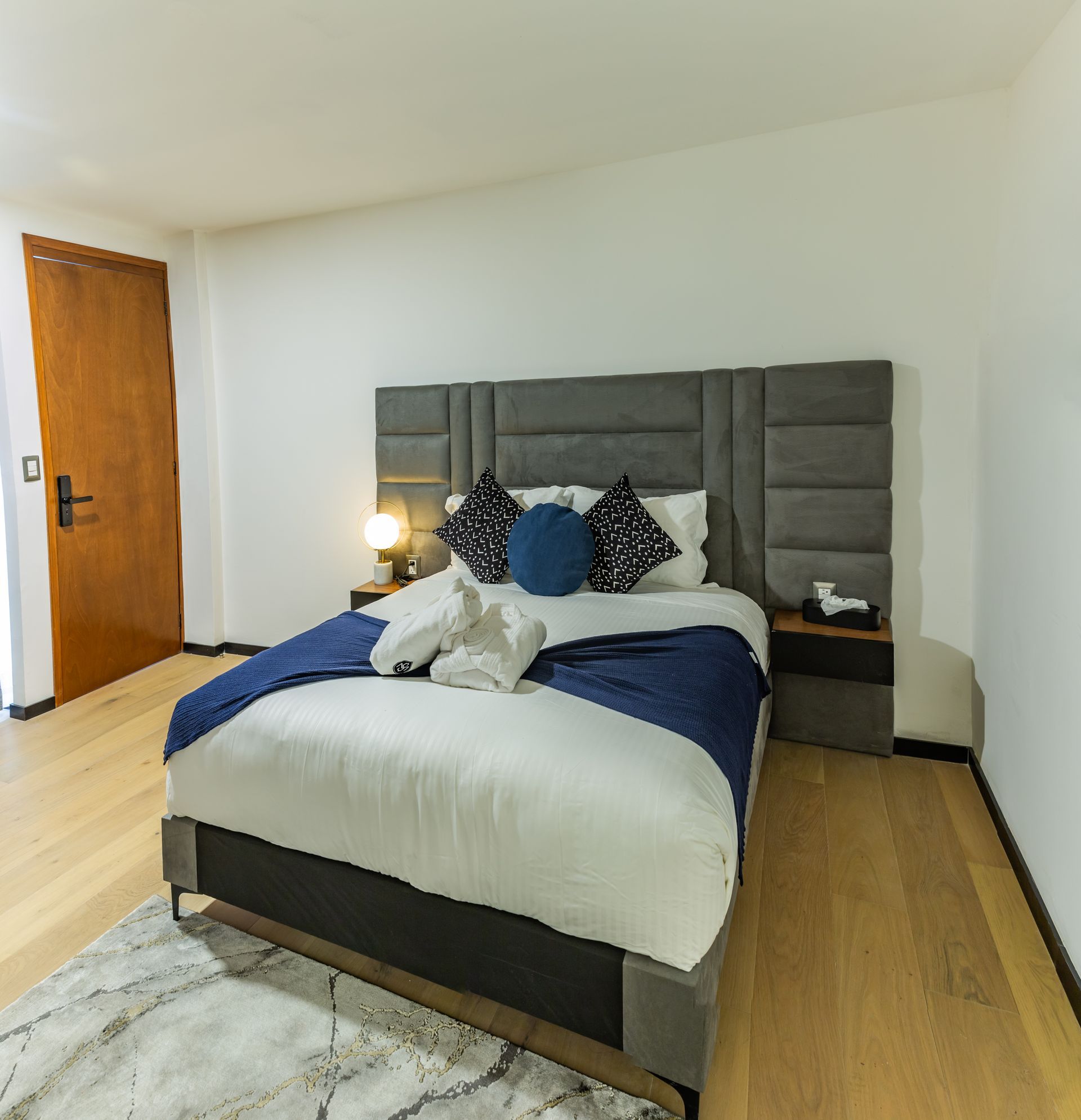 Un dormitorio con una cama grande y una alfombra en el suelo.