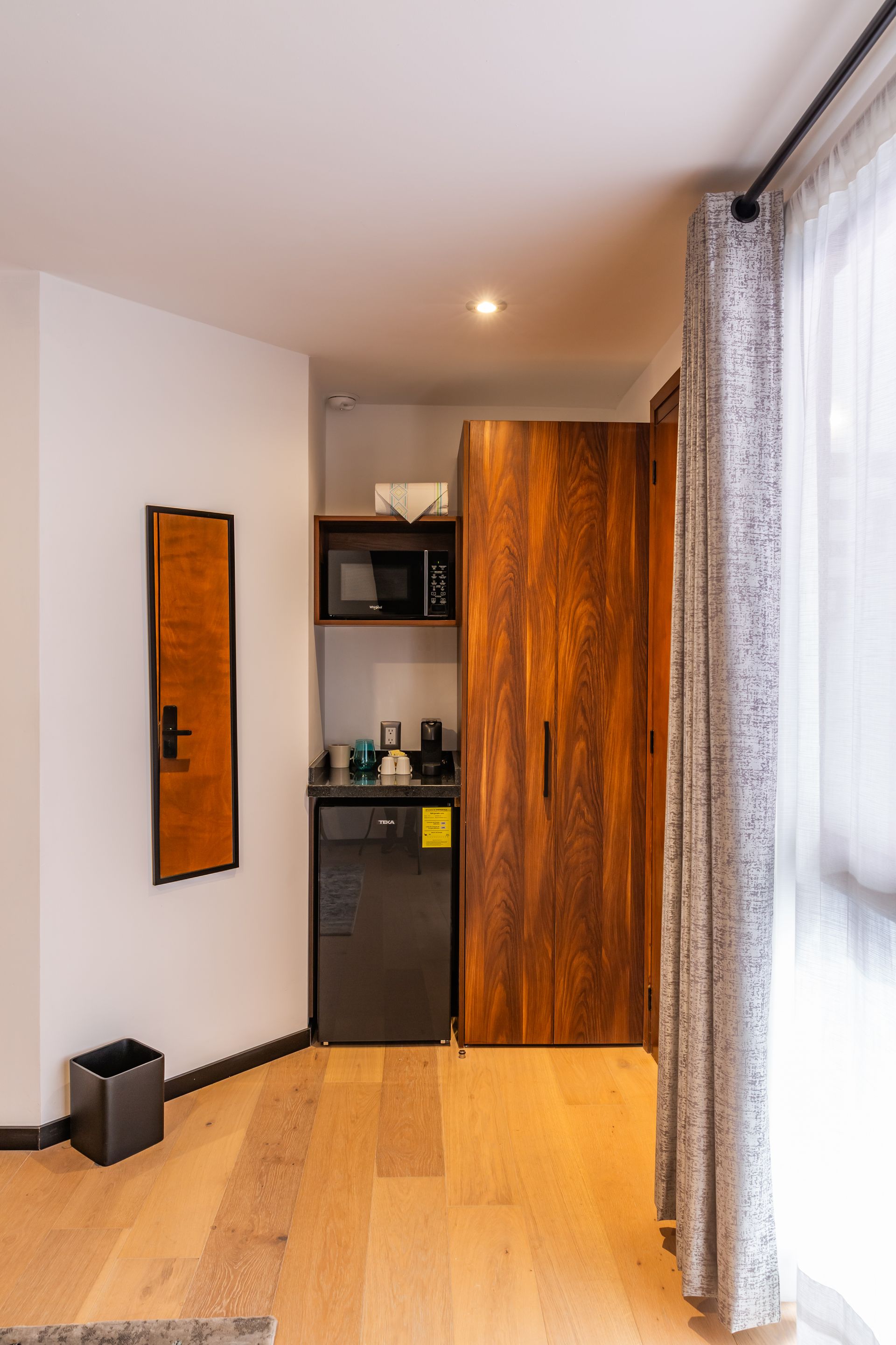 Una habitación de hotel con nevera, microondas y espejo.
