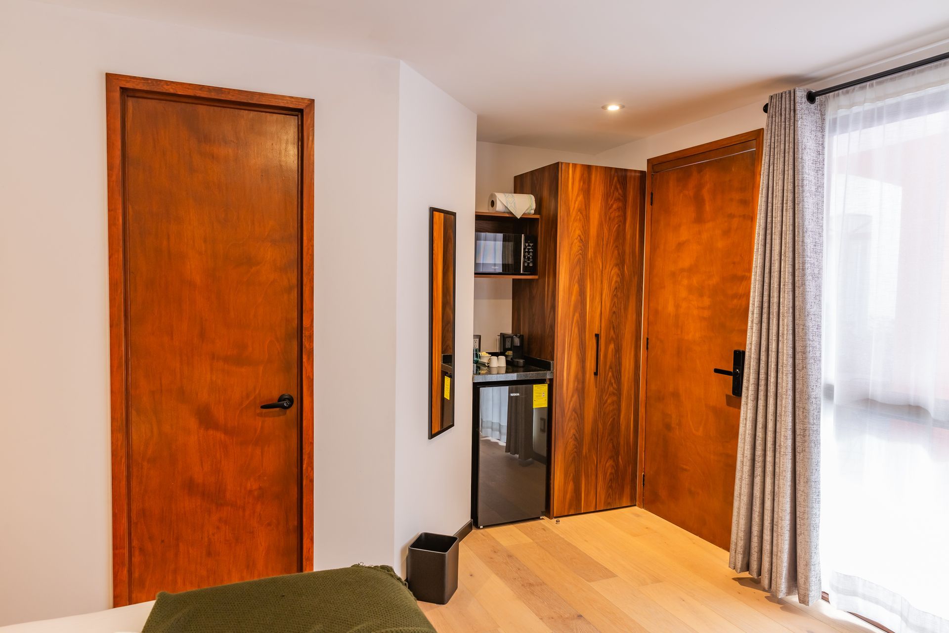 Un dormitorio con una cama, una nevera, un microondas y un espejo.