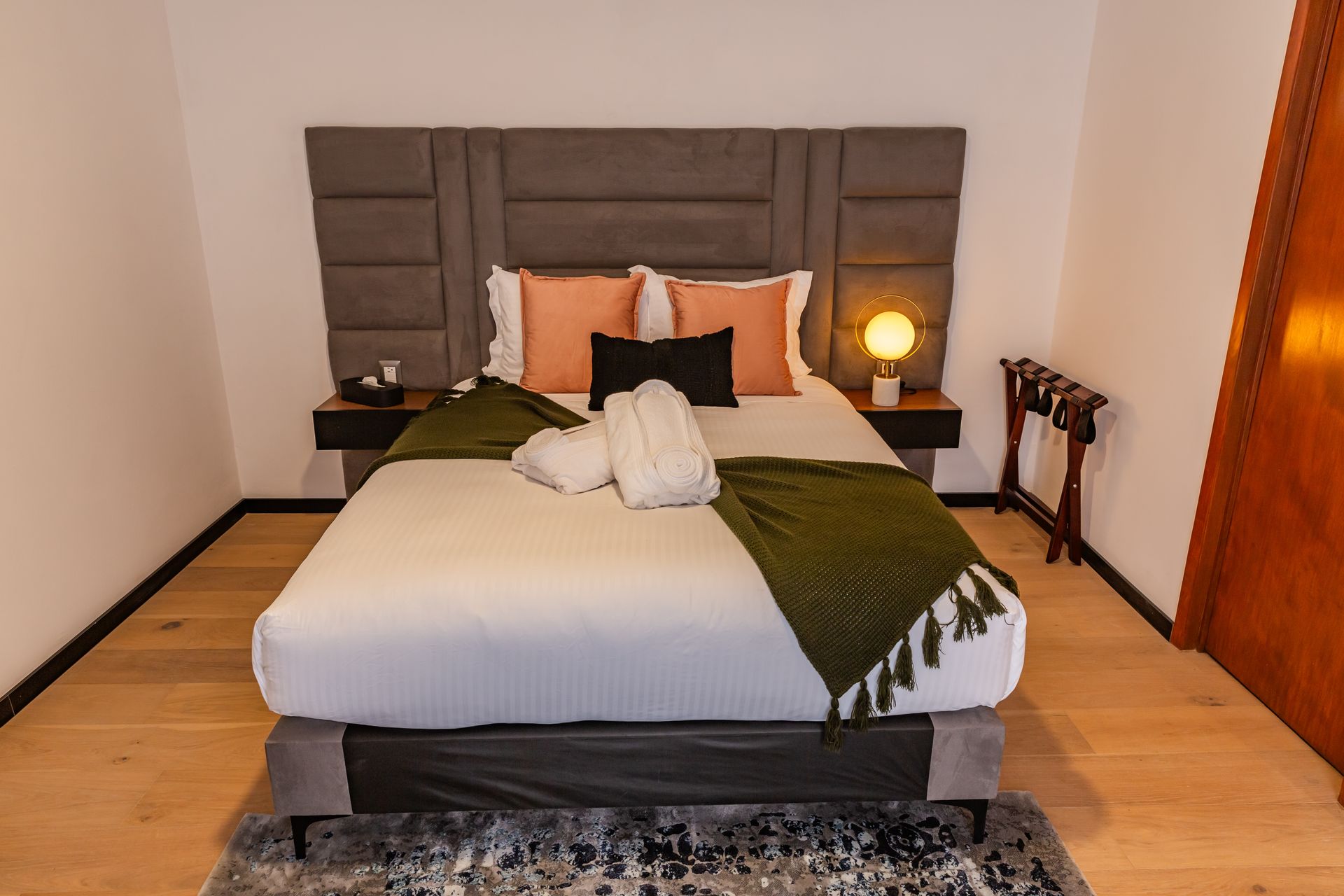 Un dormitorio con una cama grande y una alfombra en el suelo.