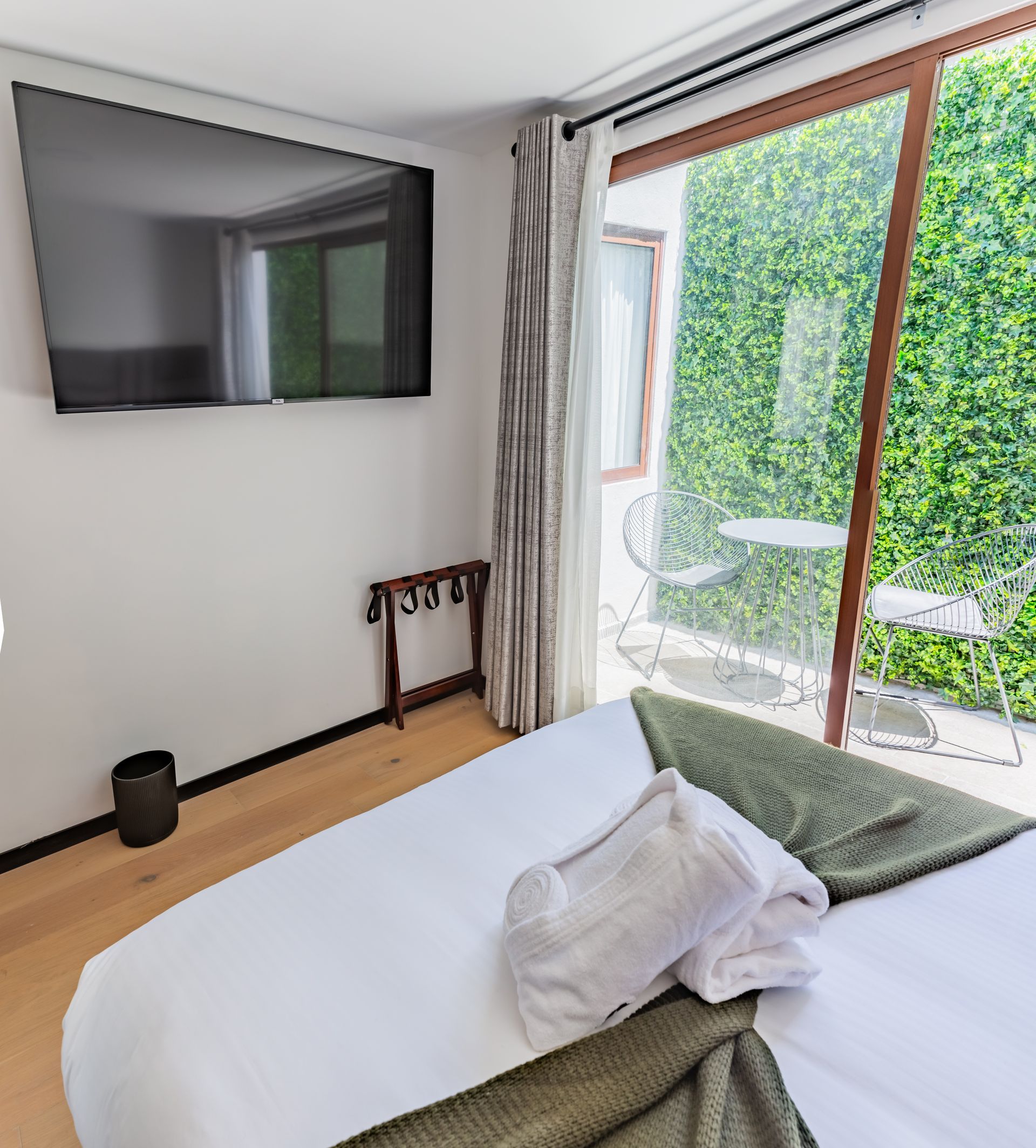 Un dormitorio con una cama, televisión y una gran ventana.