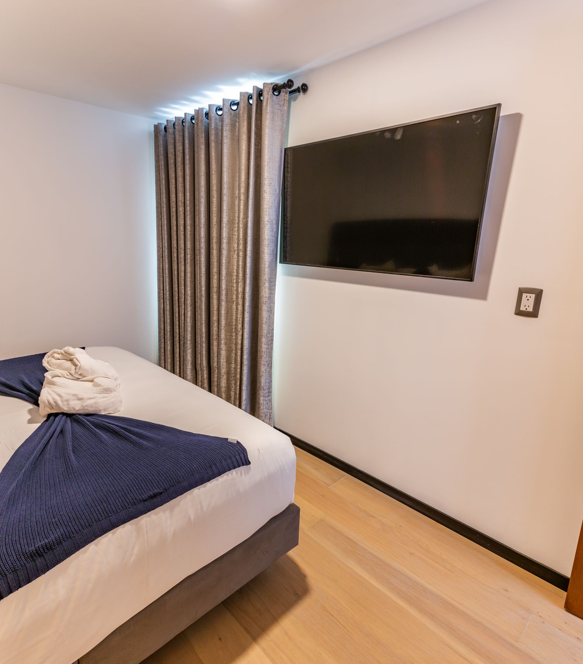 Un dormitorio con un televisor de pantalla plana grande en la pared sobre la cama.