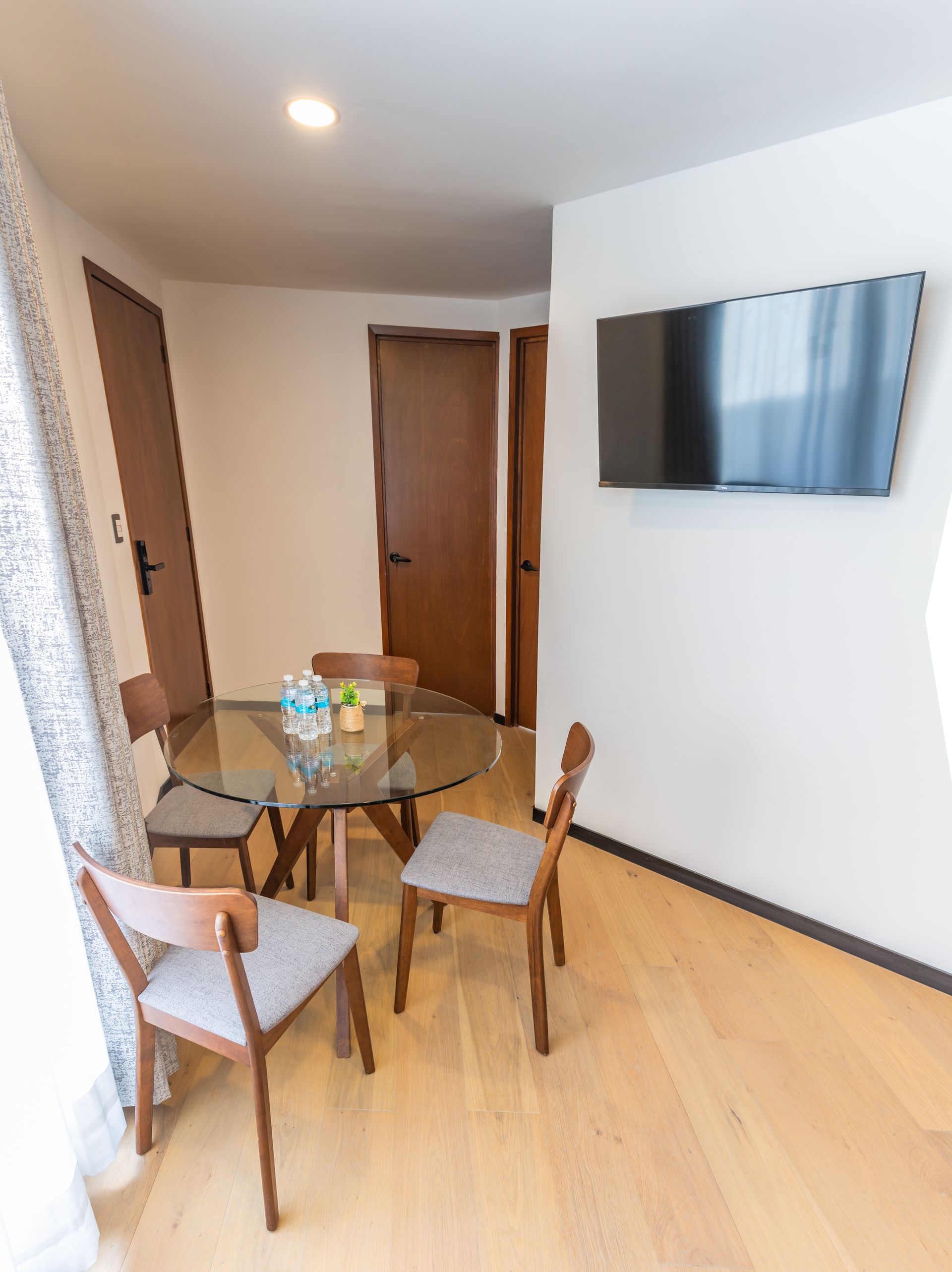 Una sala de estar con una mesa de cristal y sillas y un televisor de pantalla plana en la pared.