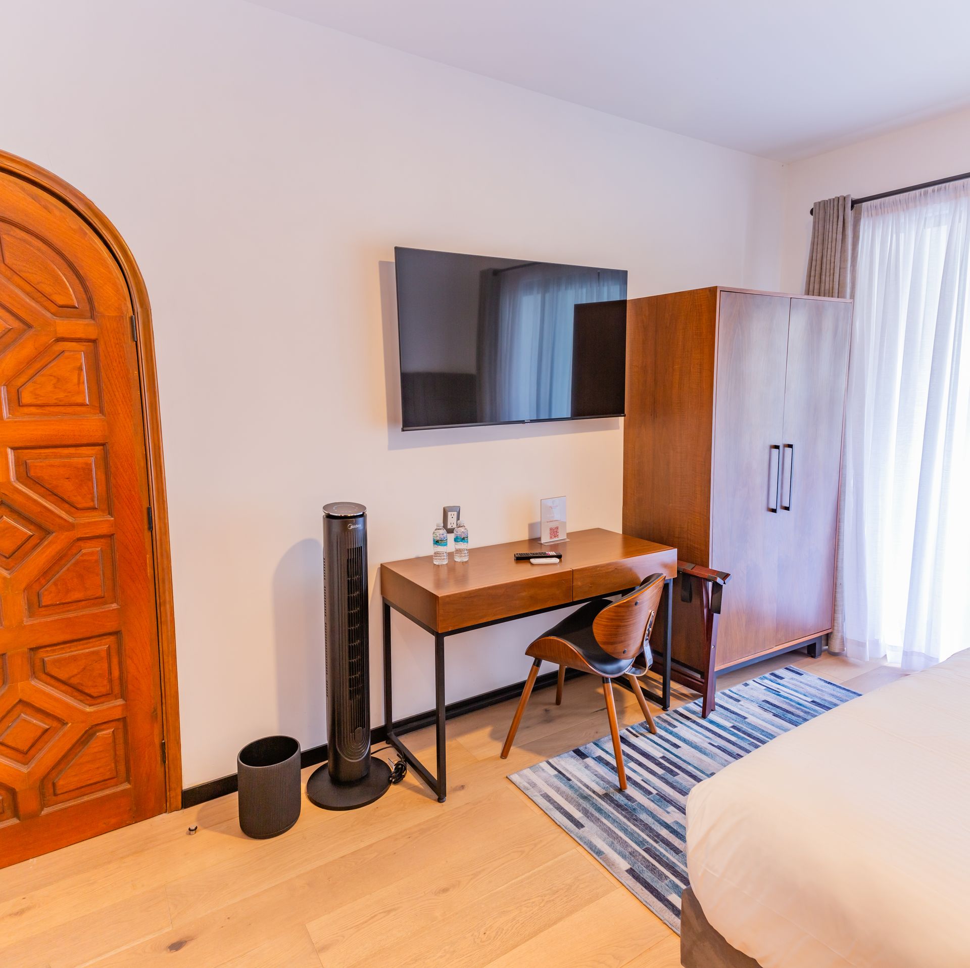 Una habitación de hotel con cama, escritorio, silla y televisión.