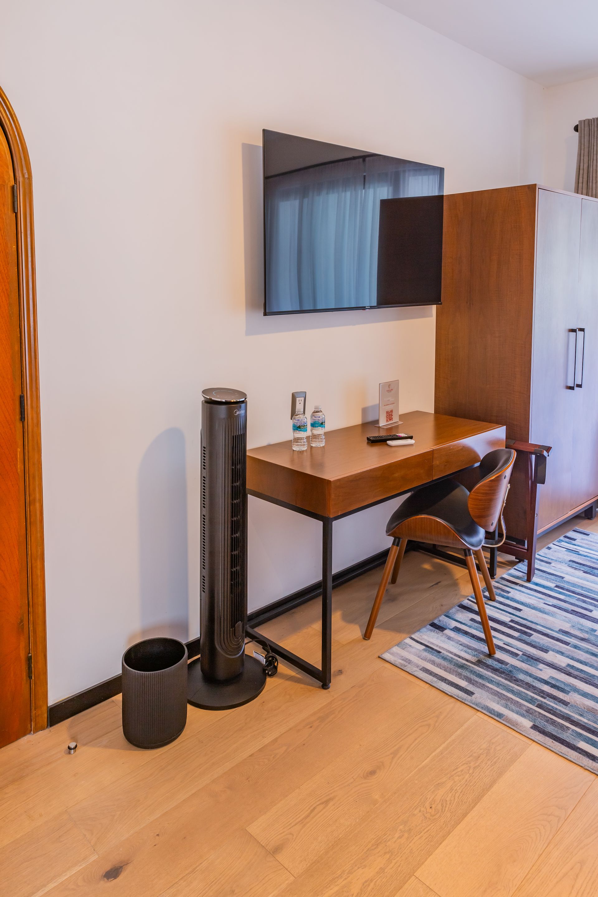 Una habitación de hotel con escritorio, silla, televisión y ventilador.