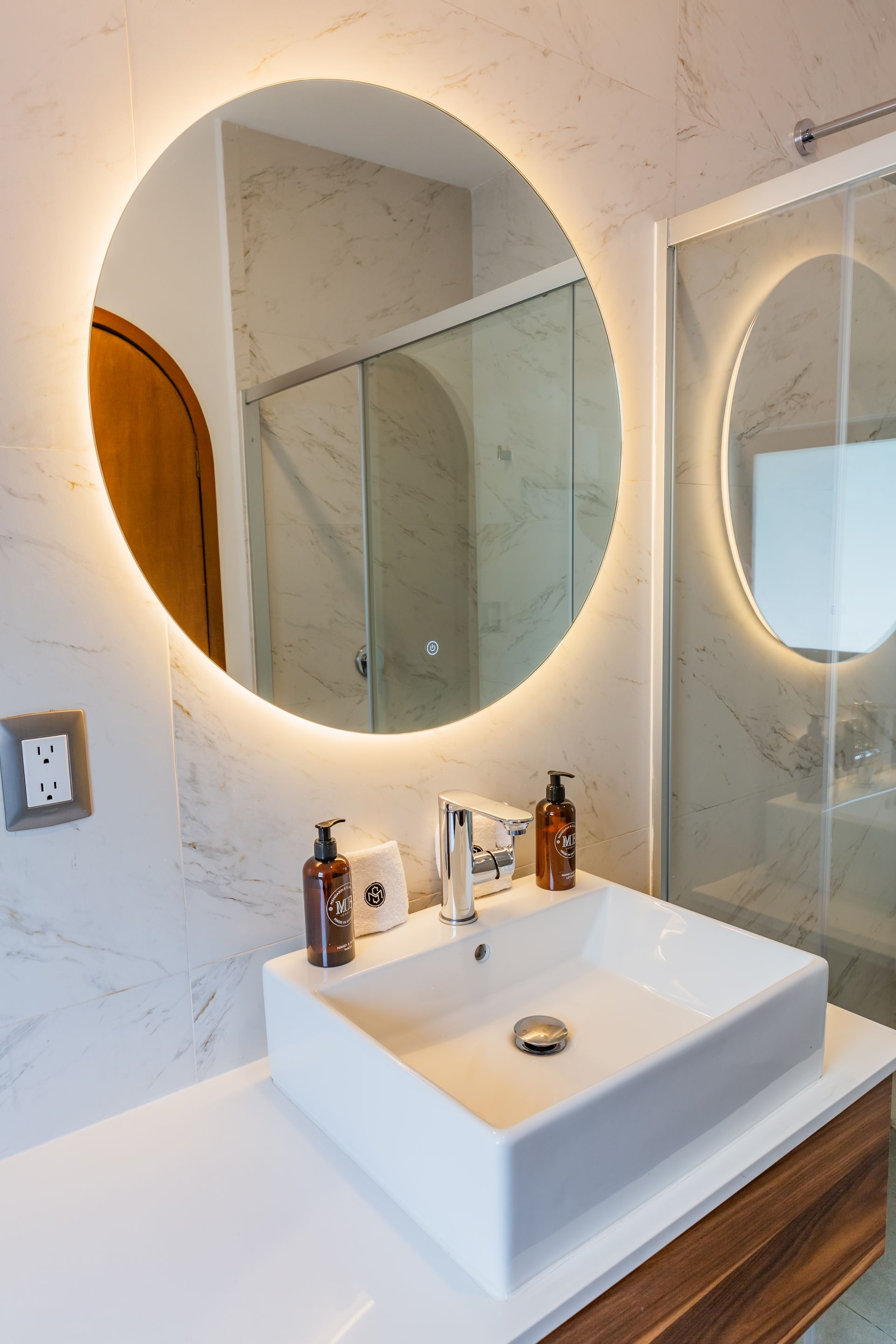 Un baño con lavabo y espejo redondo.