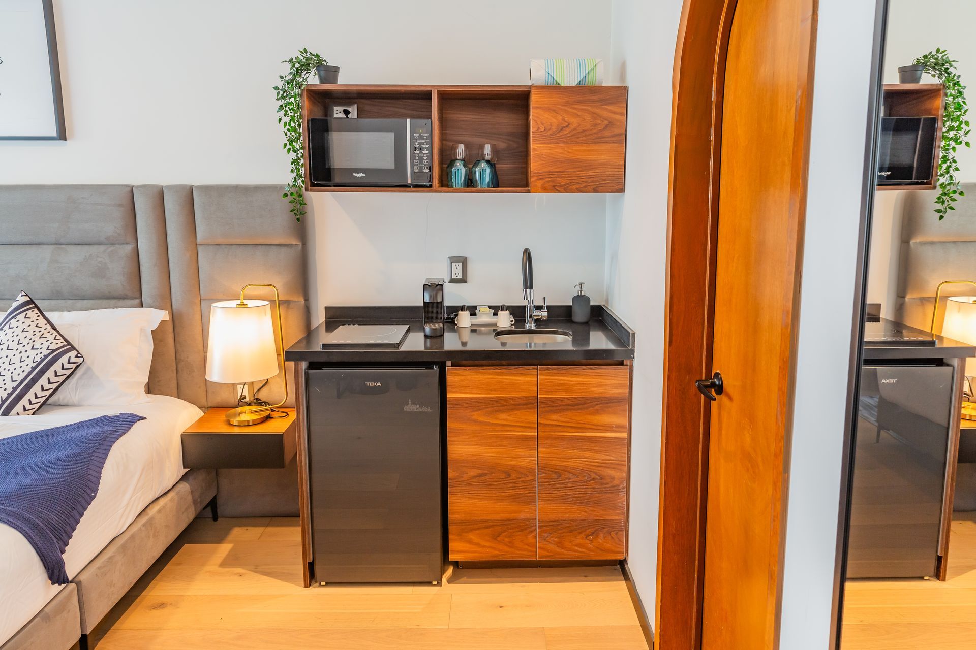 Una pequeña cocina en una habitación de hotel al lado de una cama.