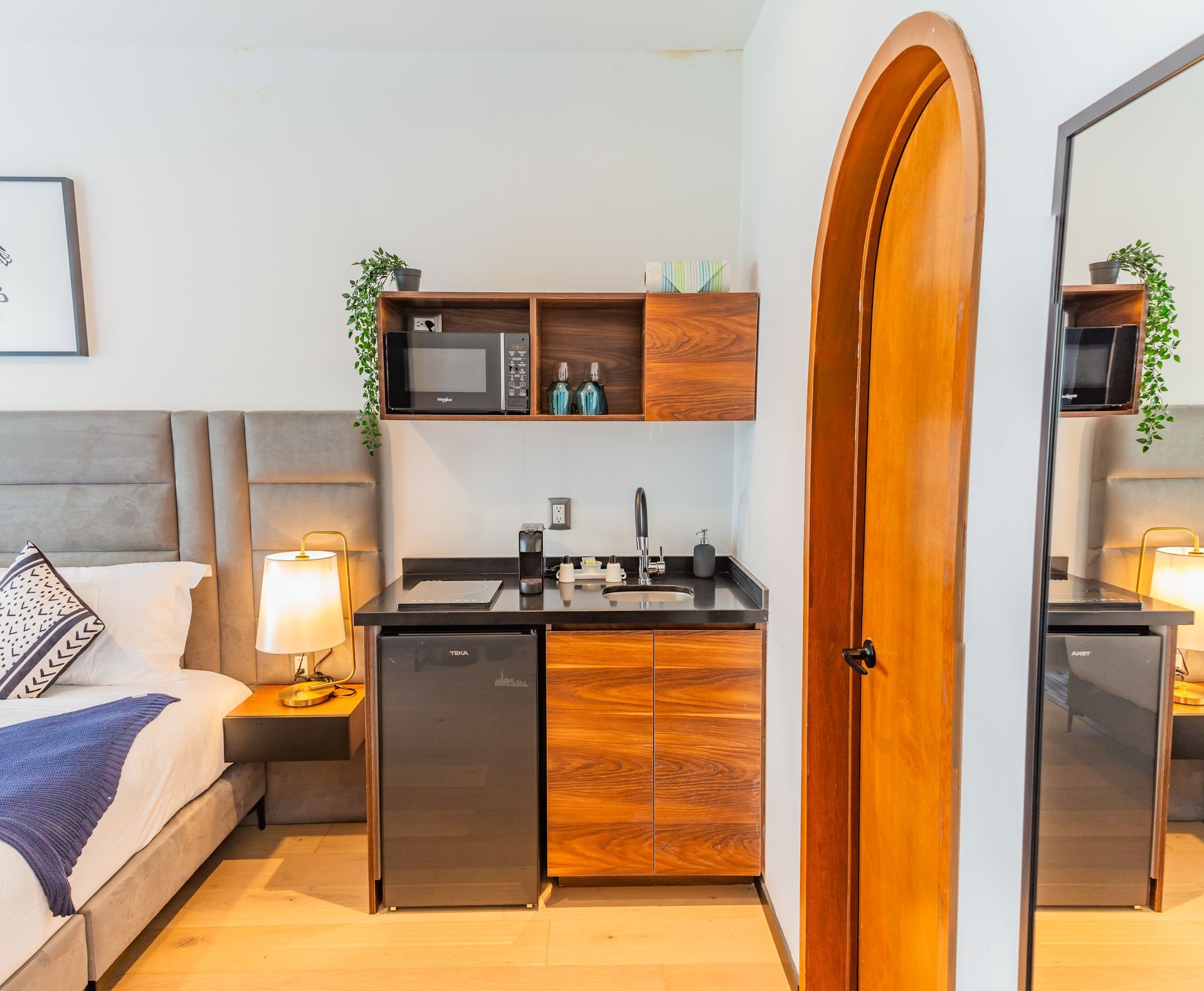 Un dormitorio con una pequeña cocina y una cama.