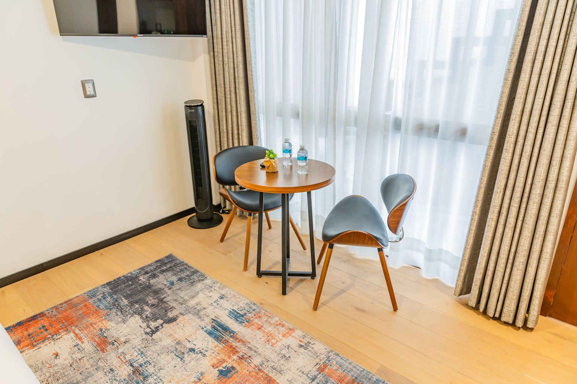 Una habitación de hotel con una mesa y sillas frente a una gran ventana.