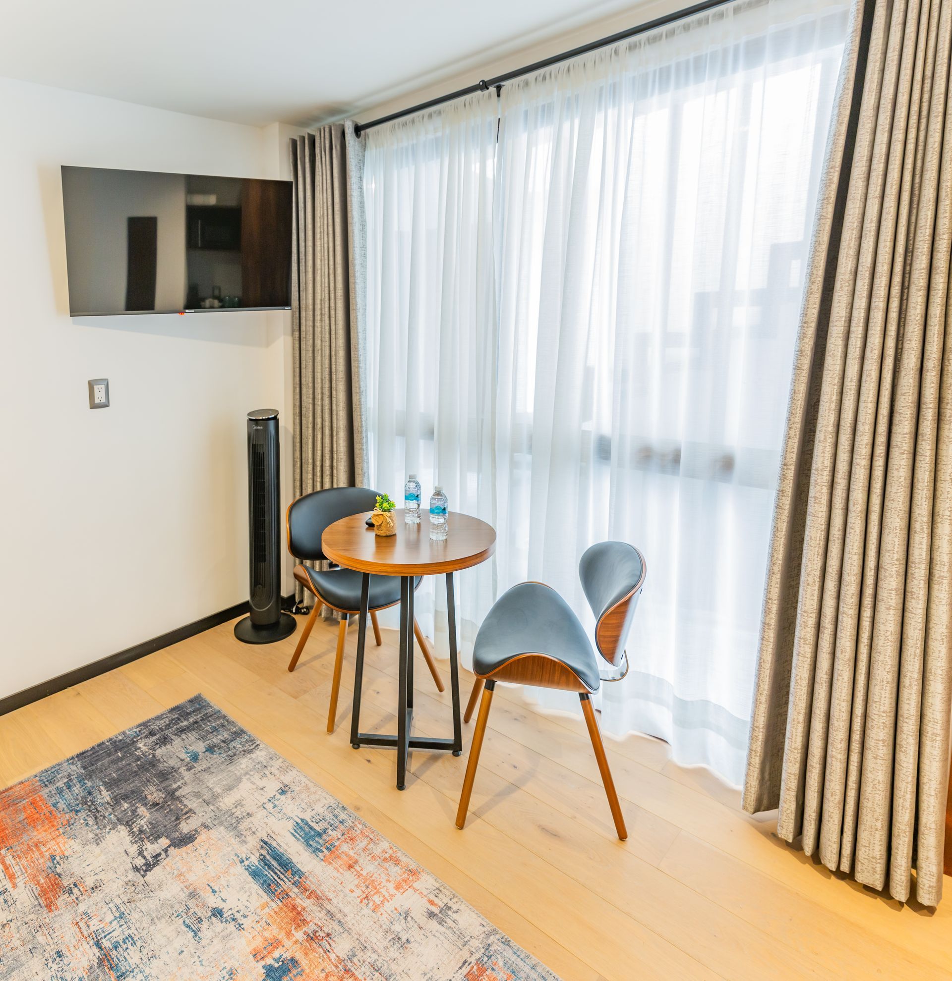 Una habitación de hotel con una mesa y sillas frente a una gran ventana.