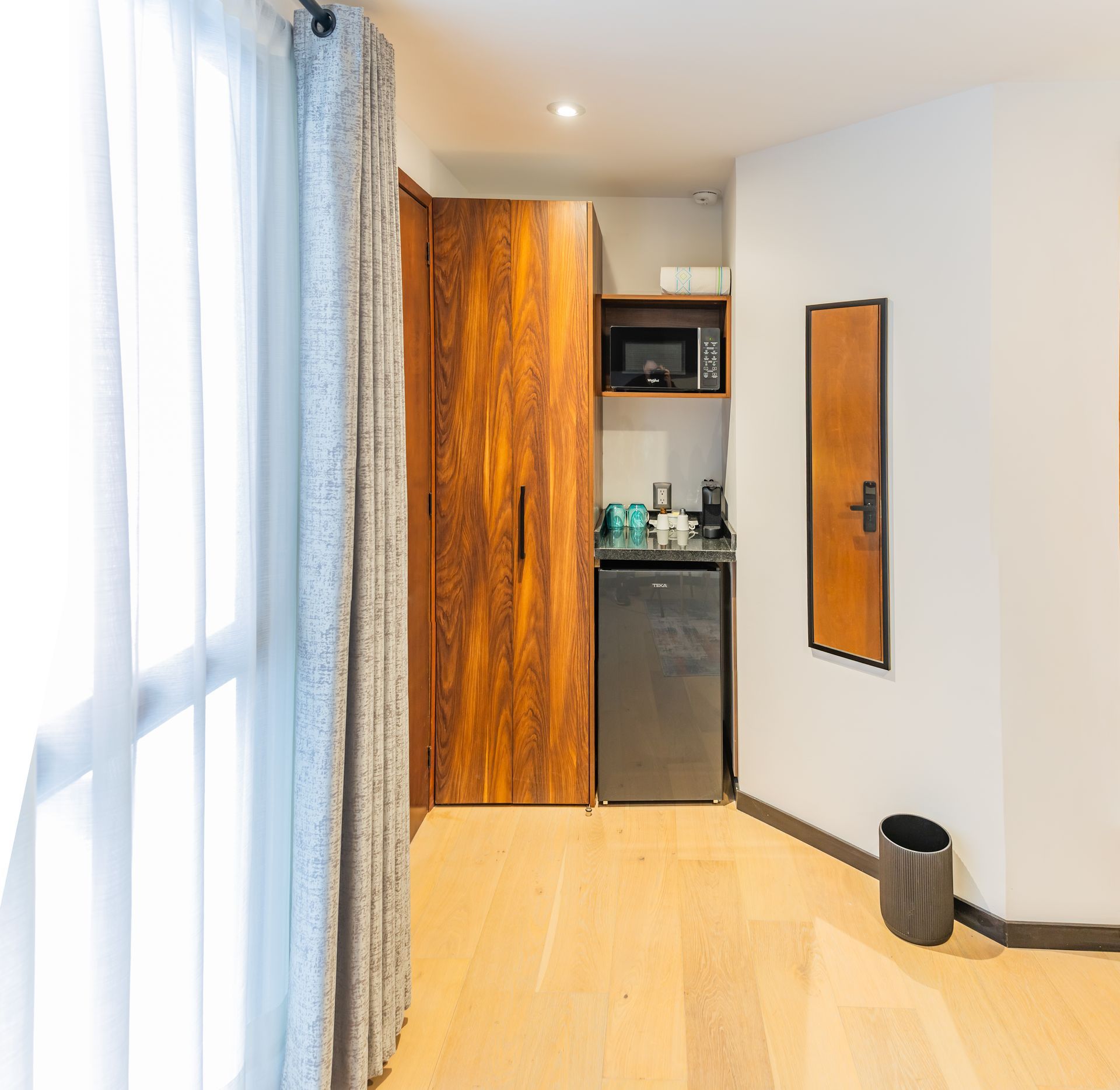 Una habitación de hotel con nevera, microondas y espejo.