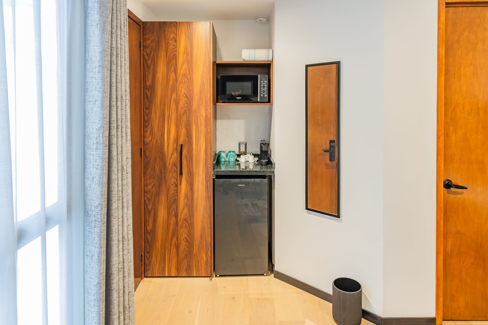 Una habitación de hotel con refrigerador, microondas y espejo.