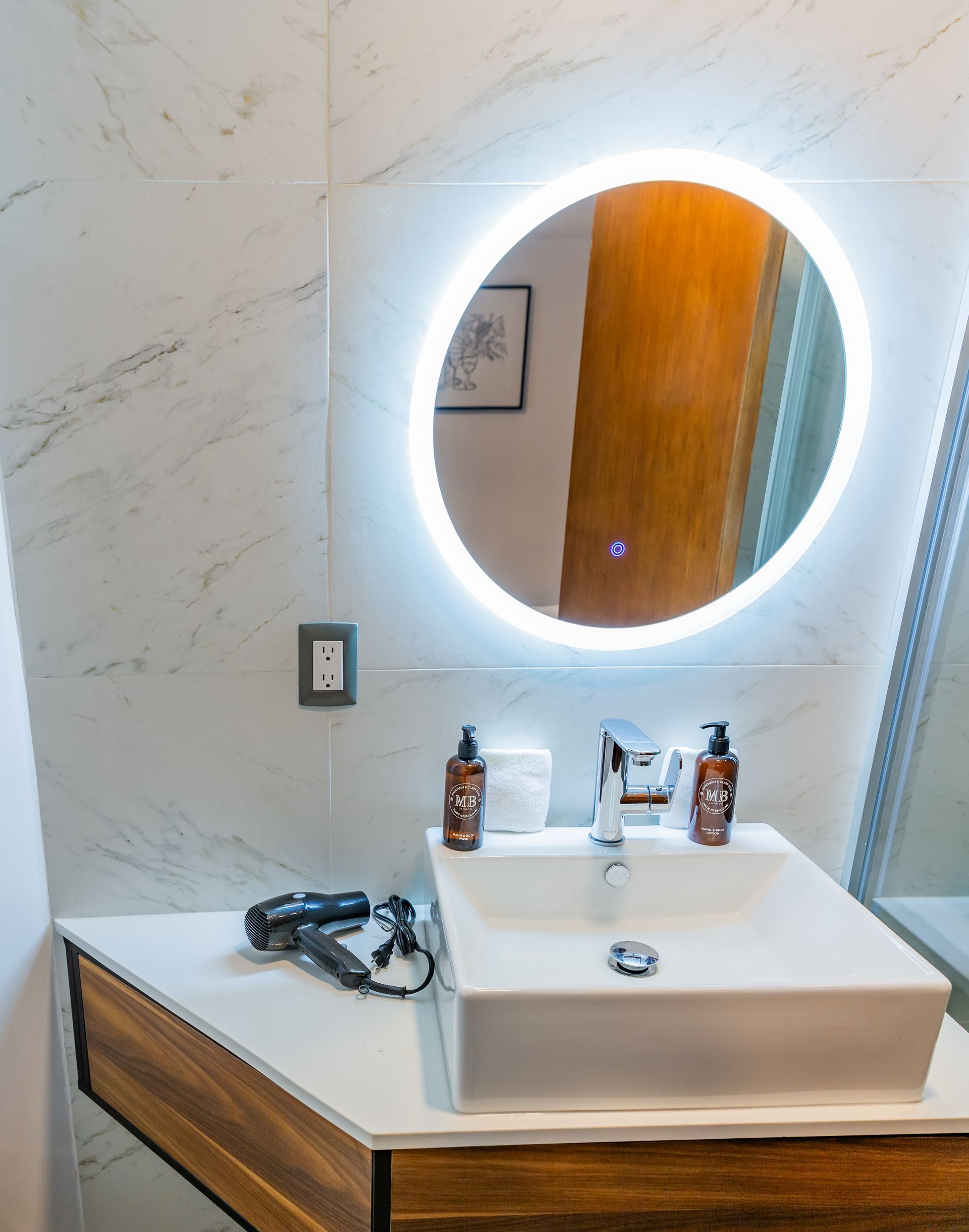 Un baño con lavabo y espejo redondo.