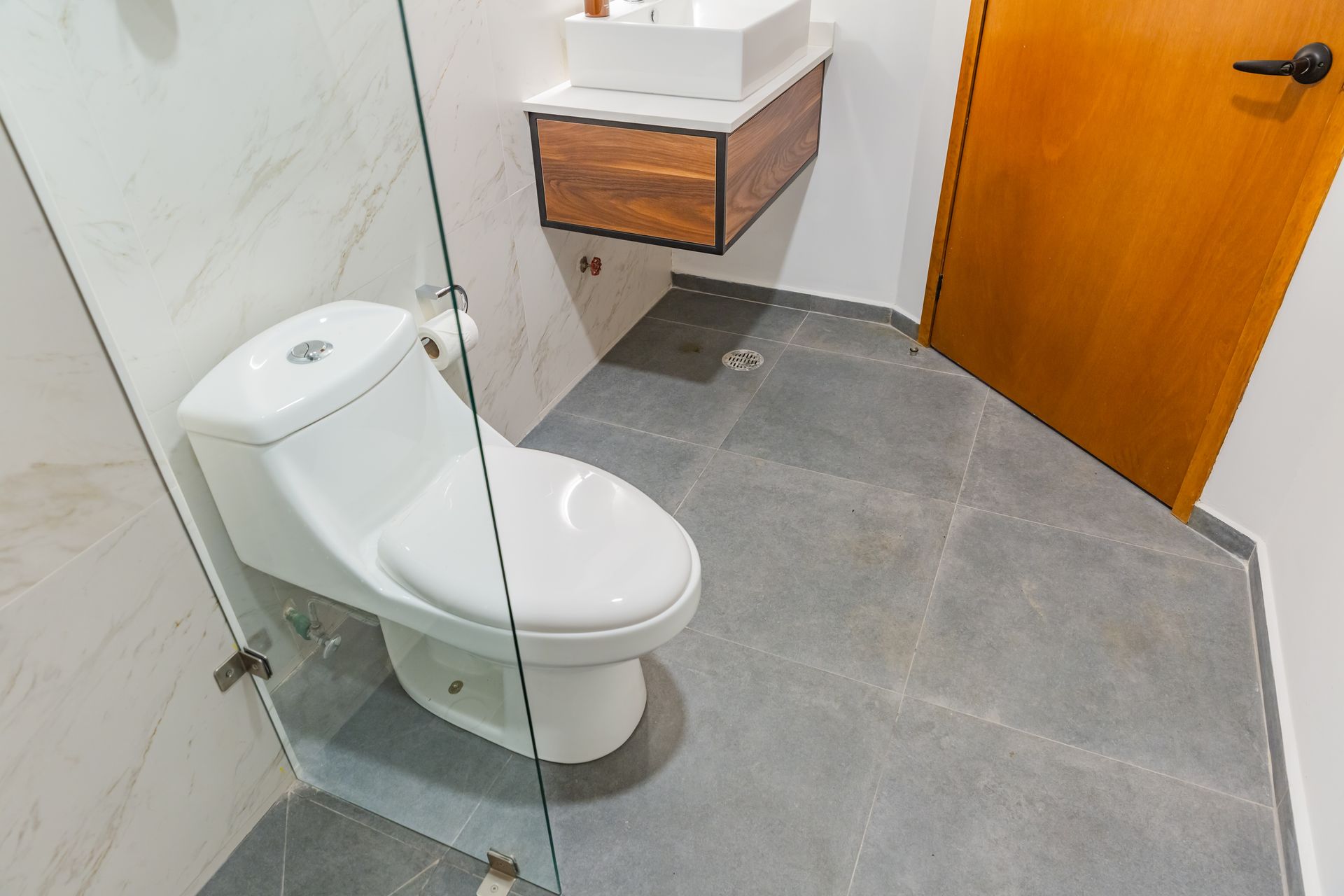 Un baño con inodoro y lavabo con puerta de cristal.