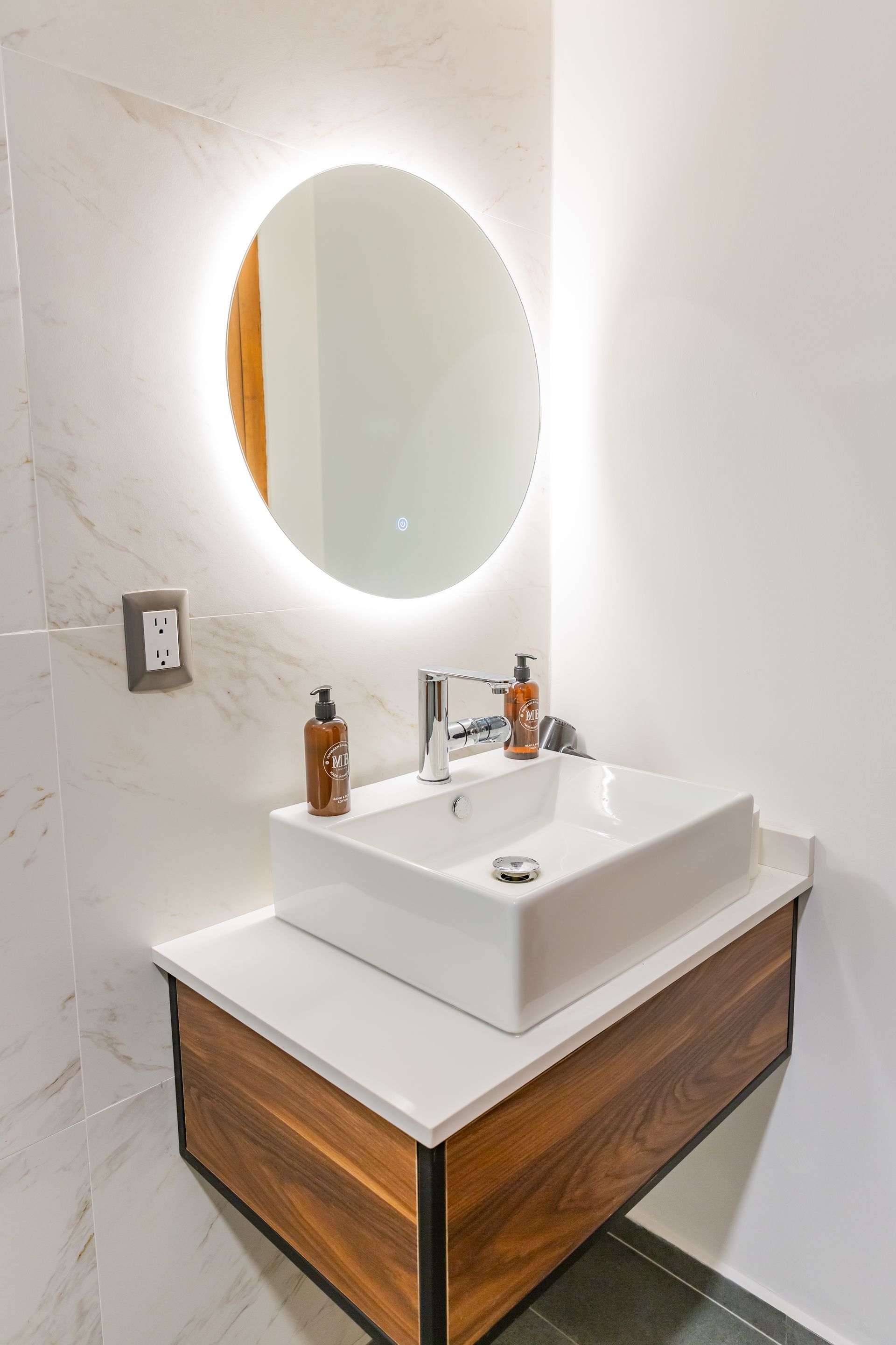 Un lavabo de baño con un espejo redondo encima.