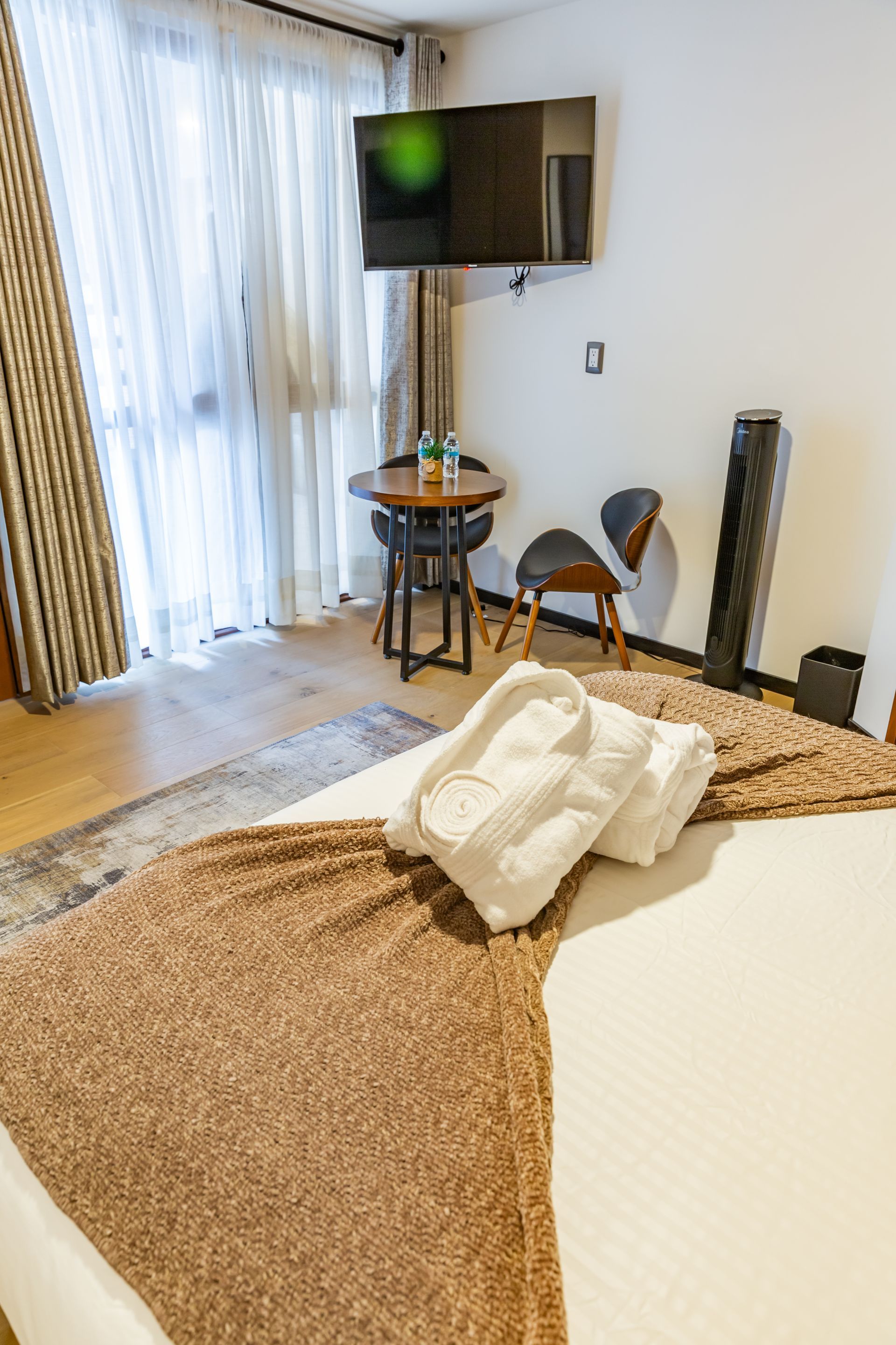 Una habitación de hotel con una cama, televisión, mesa y sillas.