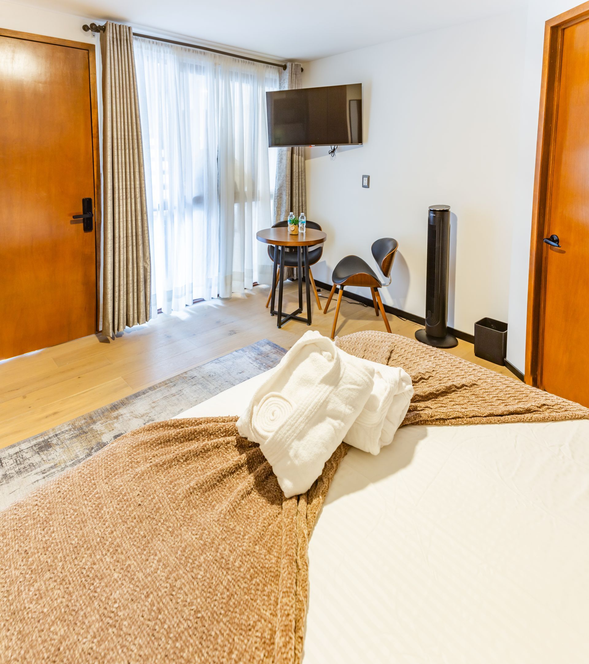 Una habitación de hotel con una cama, sillas, mesa y televisión.