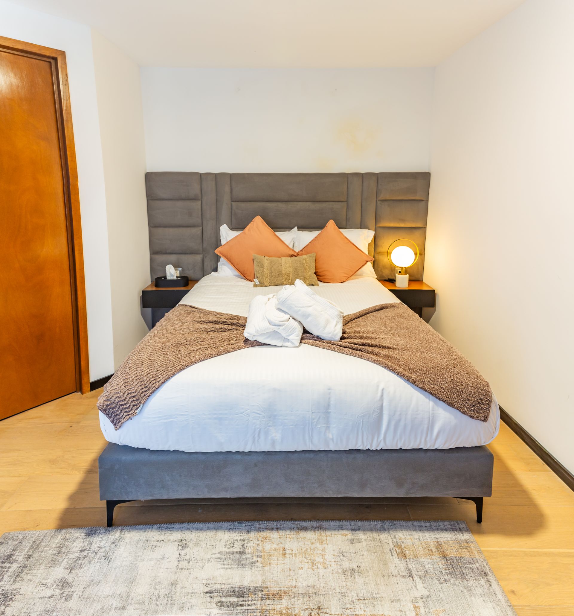 Un dormitorio con una cama y una alfombra en el suelo.