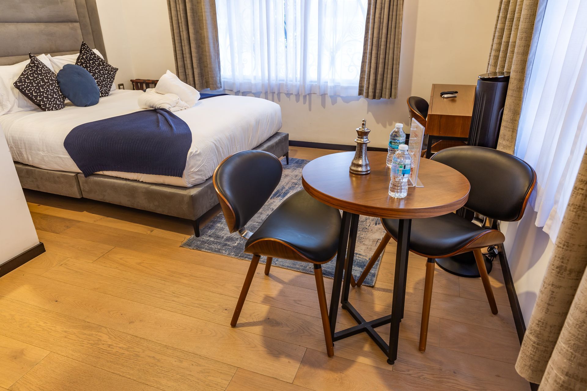 A hotel room with a table and chairs in front of a bed.