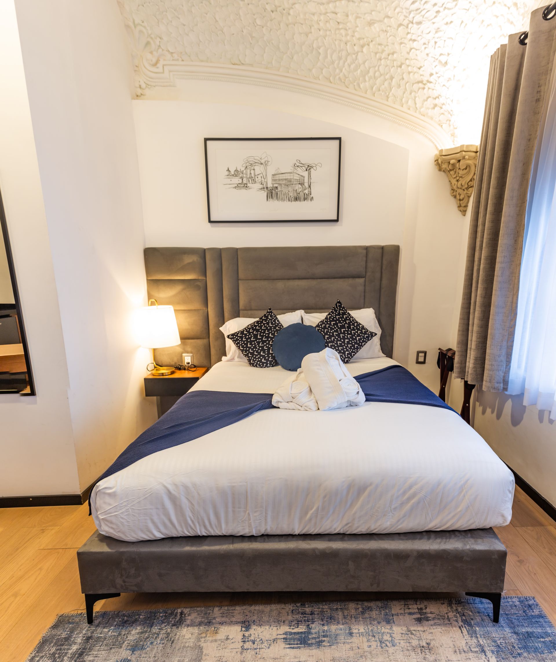A bed with white sheets and blue pillows in a hotel room