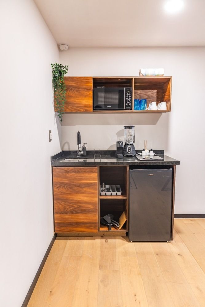 Una pequeña cocina con fregadero, frigorífico, microondas y licuadora.