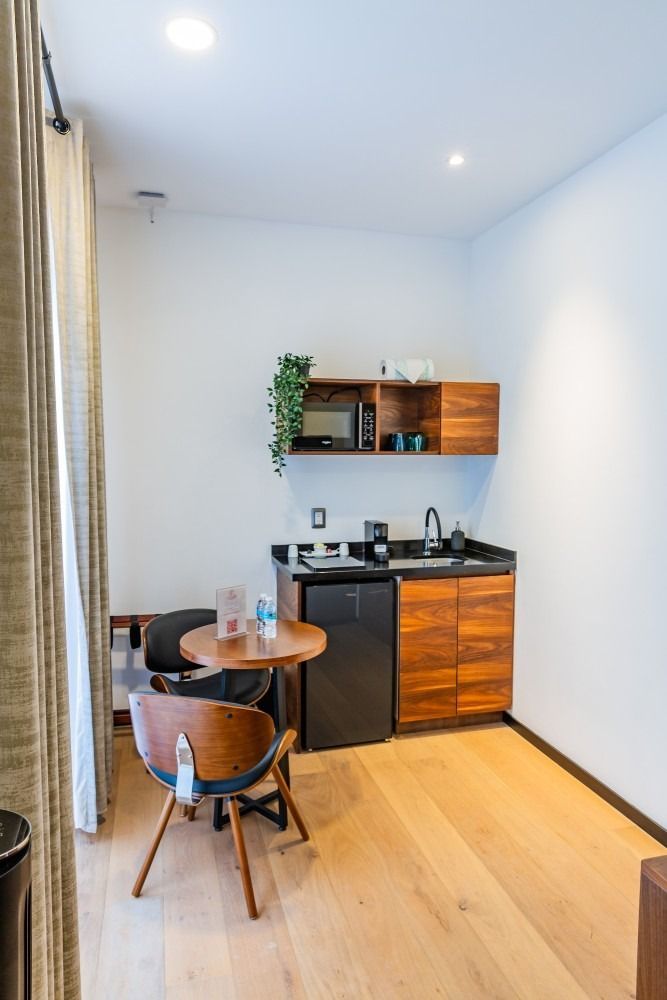 Una pequeña cocina con una mesa y sillas en una habitación de hotel.