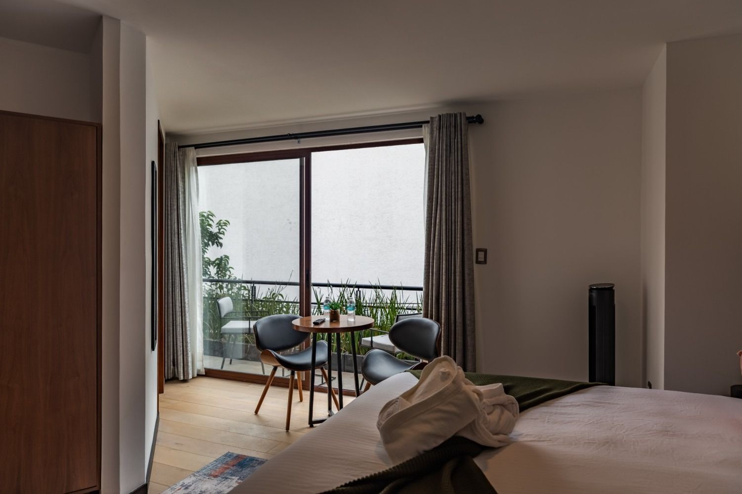 Una habitación de hotel con una cama, mesa y sillas y un balcón.
