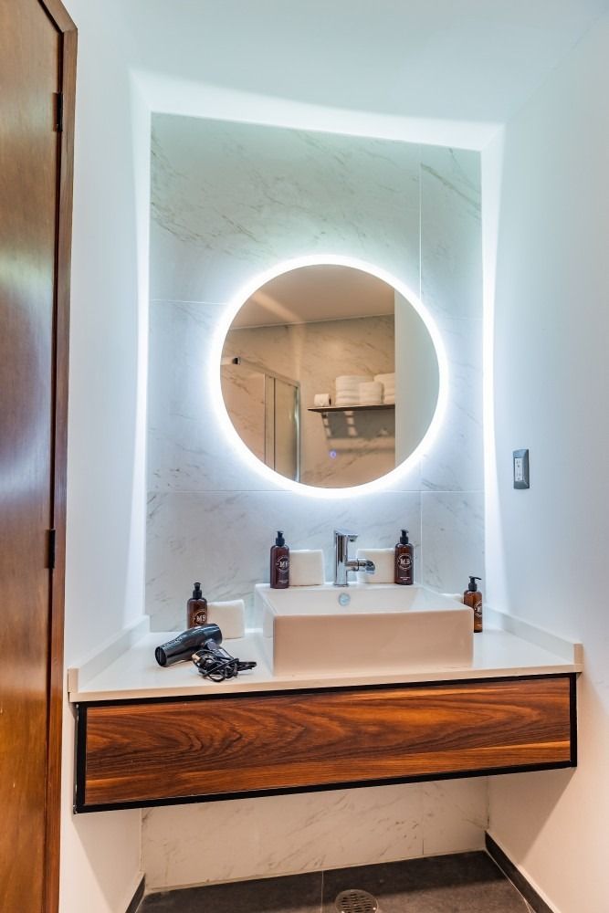 Un baño con lavabo y espejo redondo.