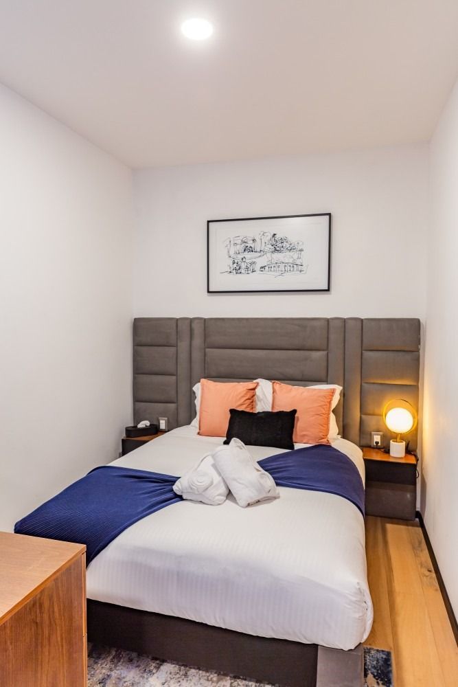 A bedroom with a bed , nightstands , and a picture on the wall.