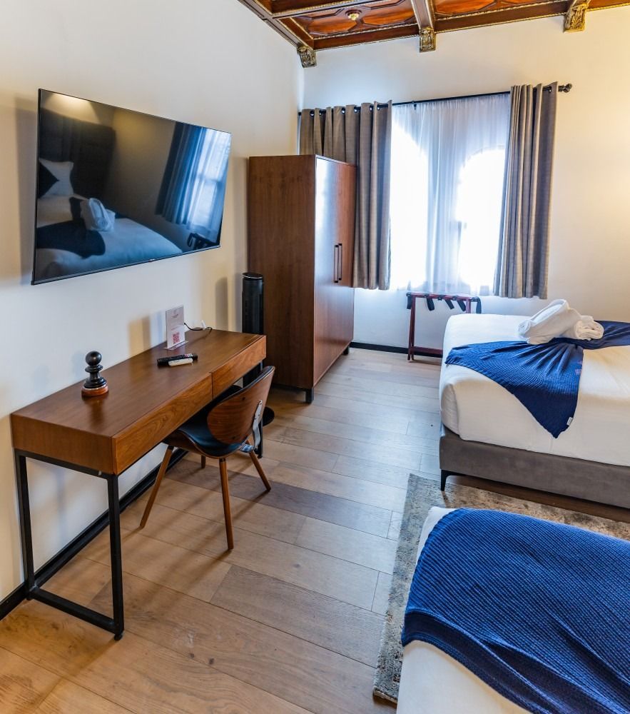 A hotel room with two beds a desk and a flat screen tv