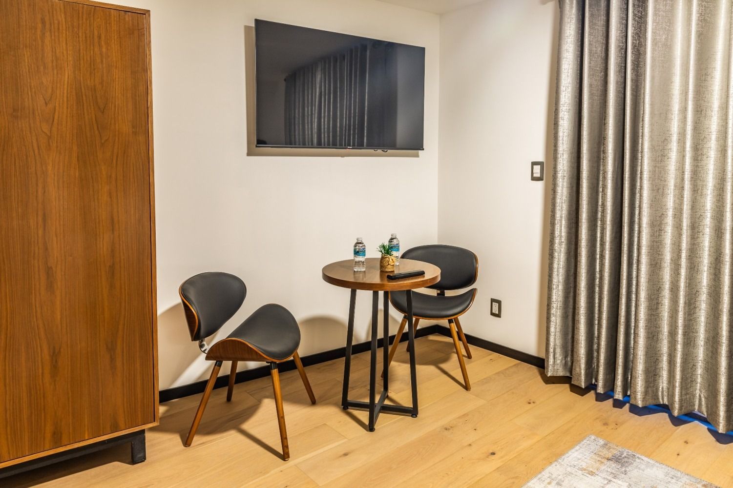Una habitación de hotel con una mesa y sillas y un televisor de pantalla plana.