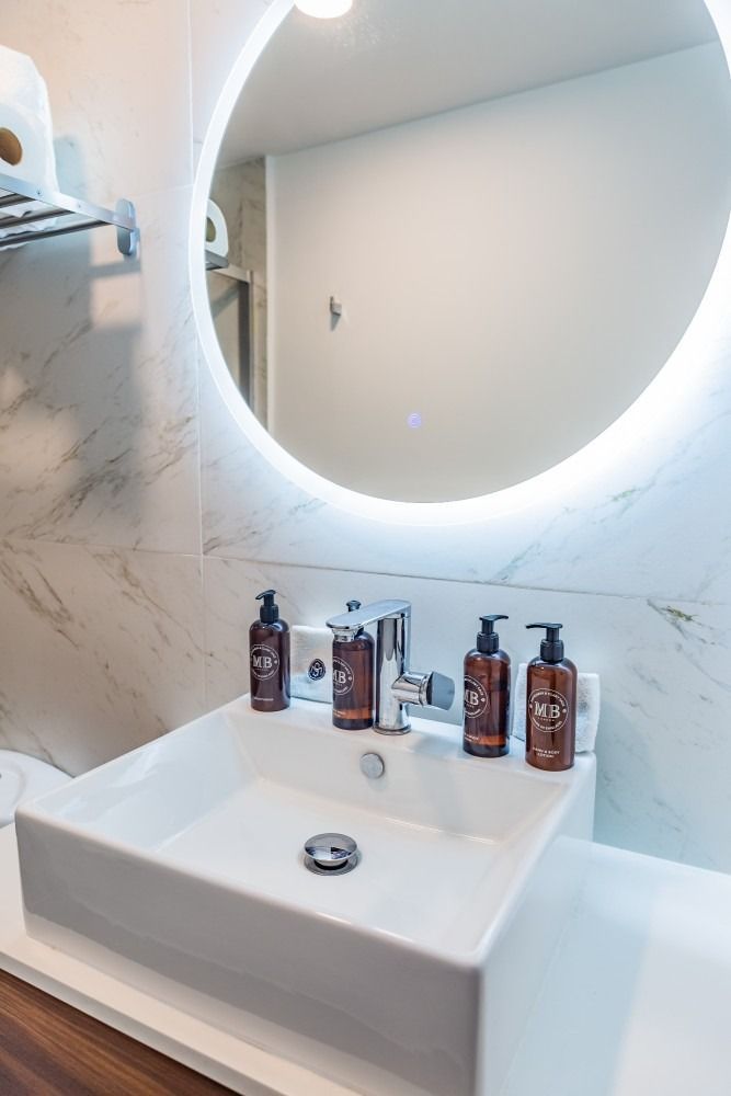 Un baño con lavabo y espejo redondo.