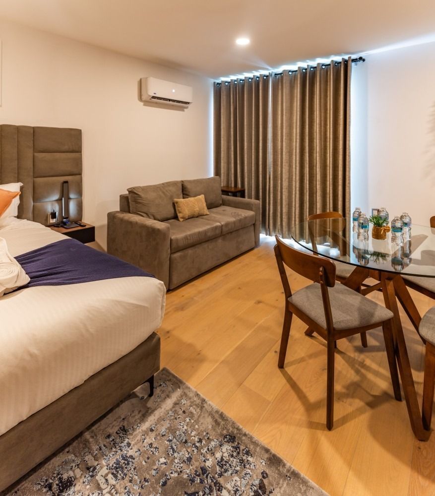 Una habitación de hotel con una cama, un sofá, una mesa y sillas.